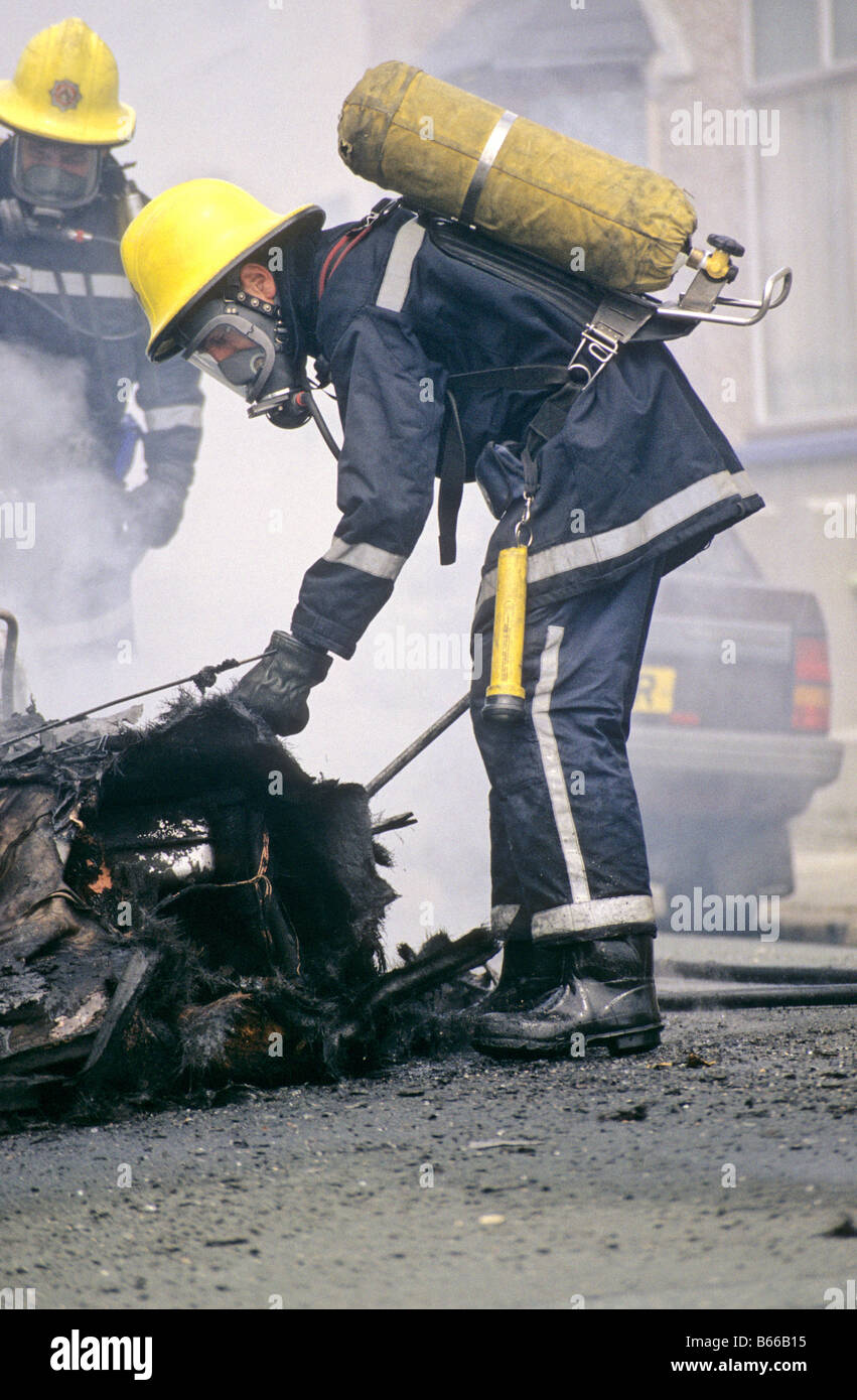 Großbritannien britische Feuerwehrmann Außerbetriebnahme Auto Feuer in Straße Atemschutzgerät tragen. Feuerwehrleute. Devon und Cornwall Feuerwehr Stockfoto