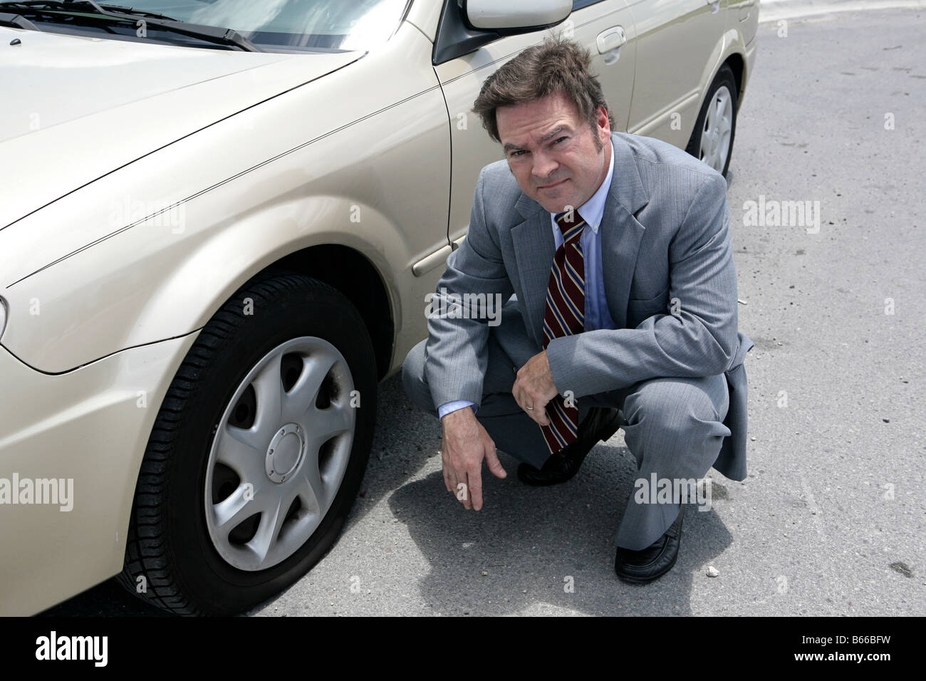 Ein Geschäftsmann mit einer Reifenpanne unterwegs sieht er verärgert Stockfoto