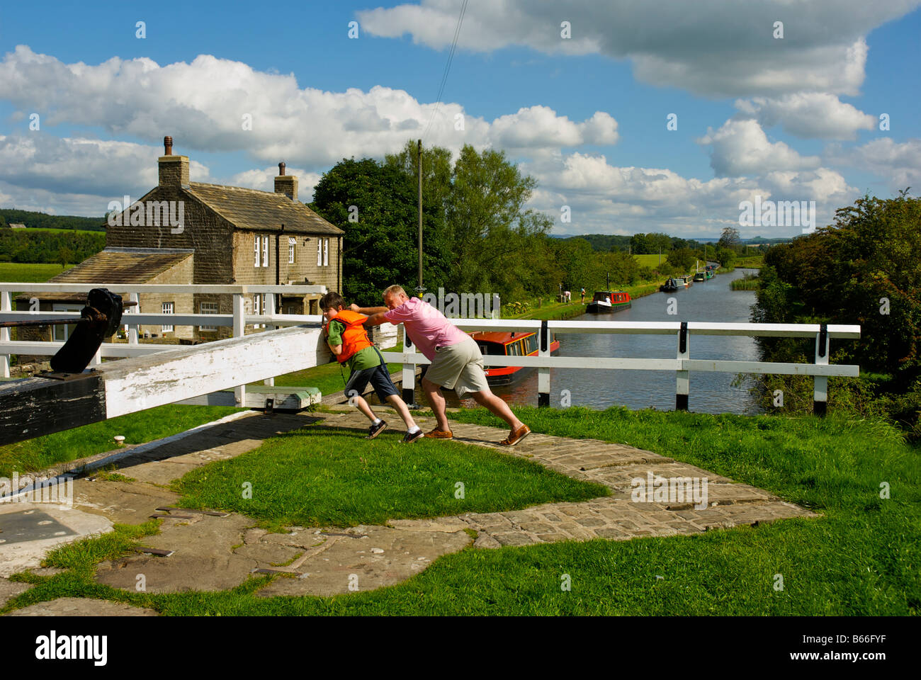 Mann und junge öffnen die Schleusen am Leeds-Liverpool-Kanal in der Nähe von Gargrave, North Yorkshire, England UK Stockfoto