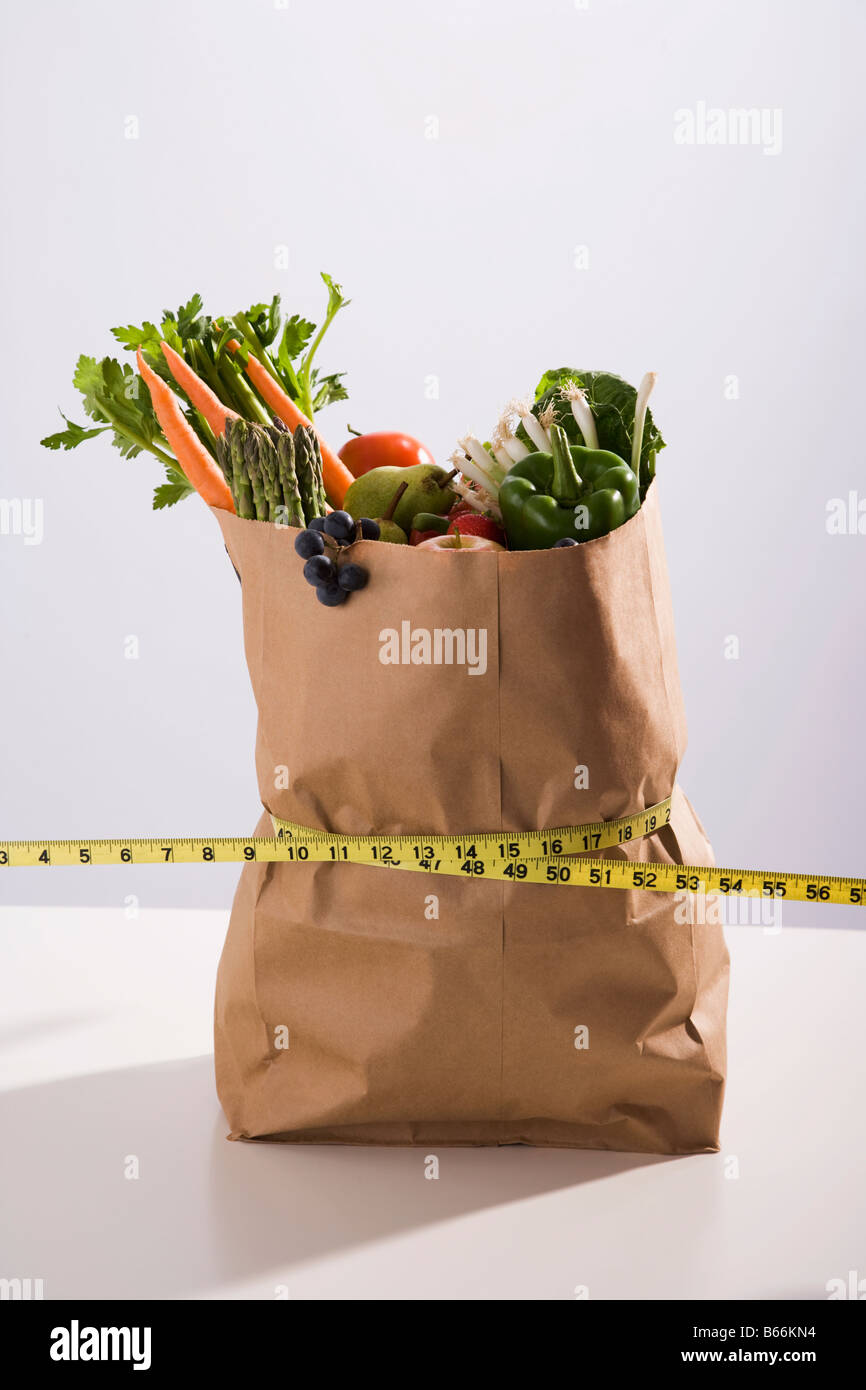 Maßband umwickelt Papiertüte gefüllt mit Obst und Gemüse Stockfoto