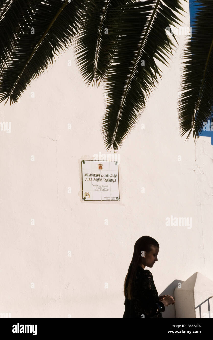 schönes junges Mädchen gekleidet in schwarz mit weißen Wand vor und Palm Blätter auf der Oberseite im Süden spanisches Dorf genommen. Stockfoto