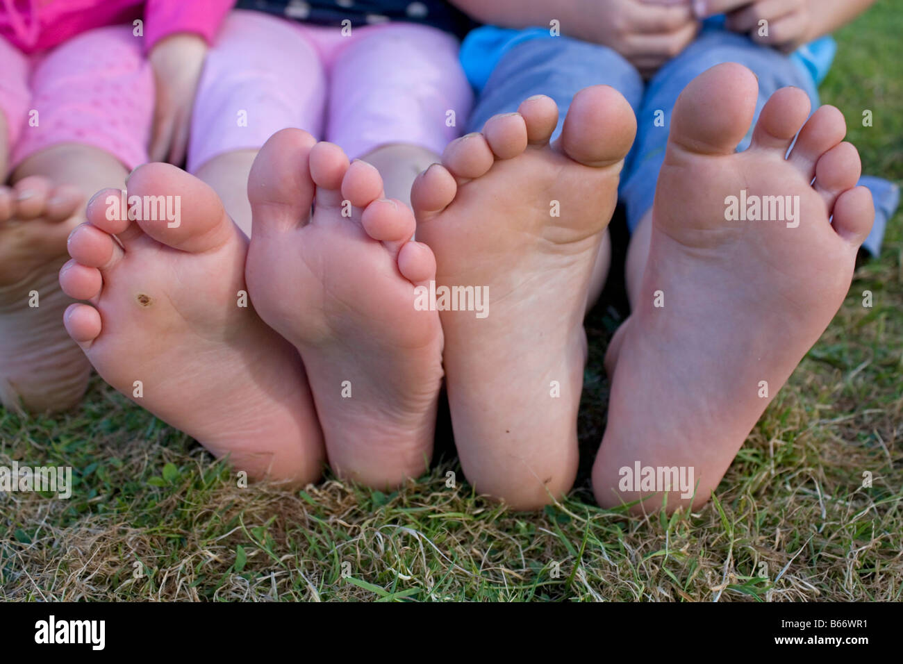 Zwei Paare Kinder barfuß auf dem Rasen UK hautnah Stockfoto