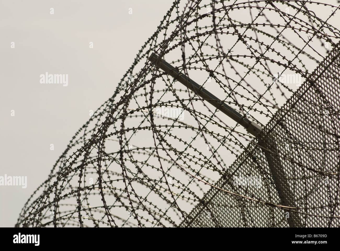 Stacheldraht und Stacheldraht auf einem privaten Gefängnis Zaun Stockfoto