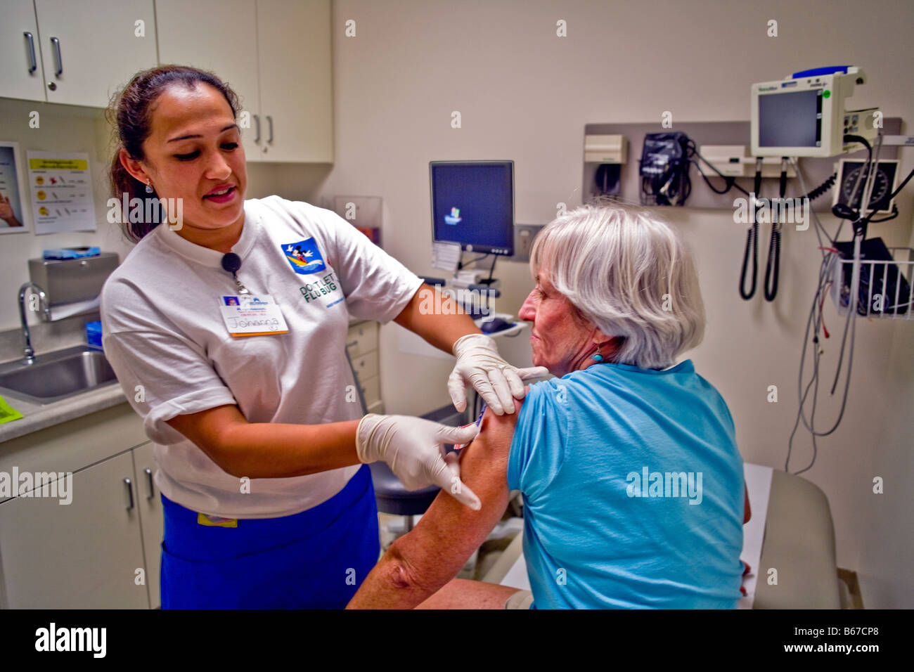 Ein Hispanic Medizintechniker gilt eine Bandage nach Verabreichung eine Grippeschutzimpfung in einer Mitte in einer California-Klinik im Alter von Stockfoto