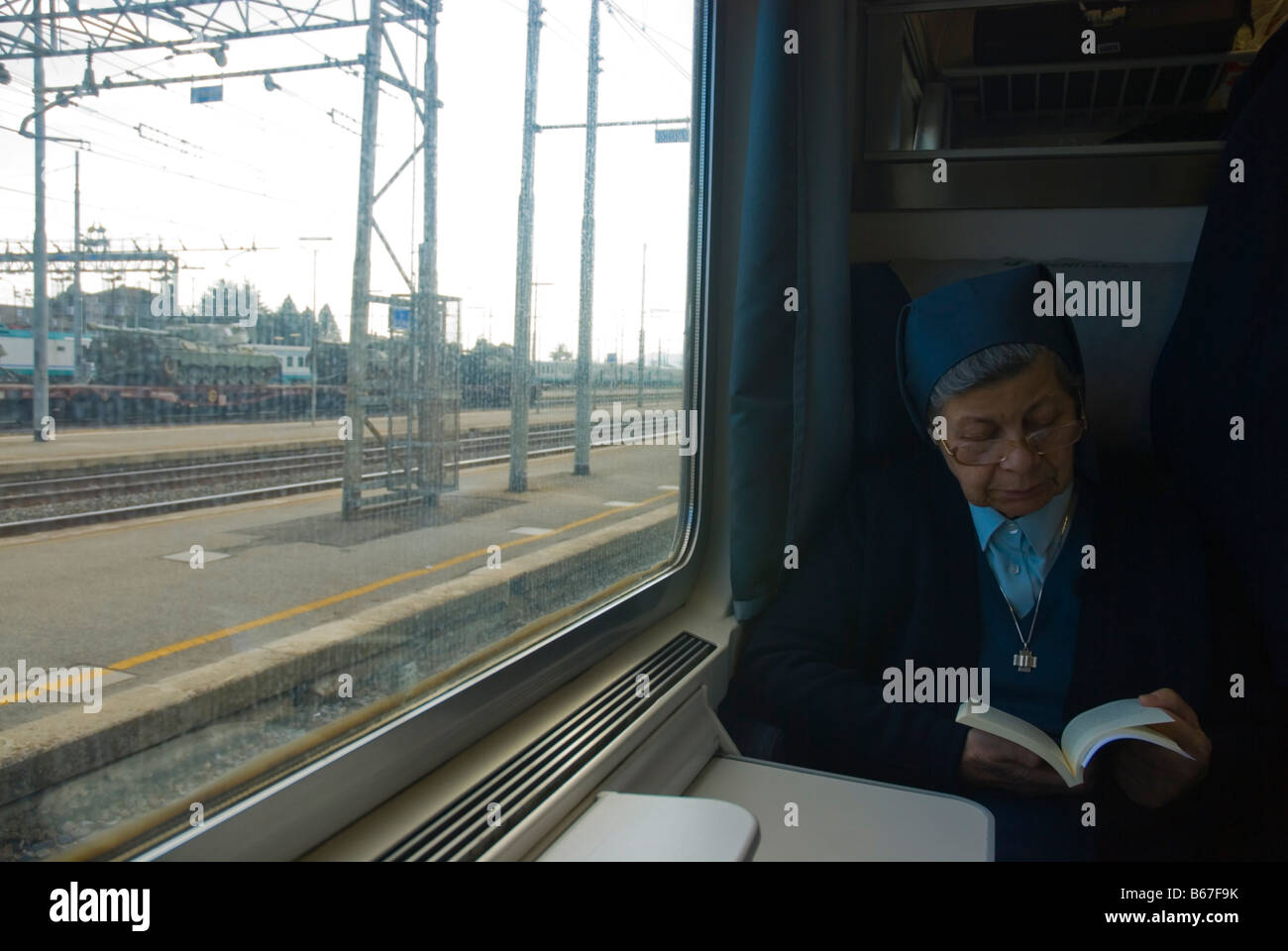Nonne in einem Zug am Bahnhof Chiusi mit Panzer und andere militärische Ausrüstung außerhalb Europas Italien lesen Stockfoto