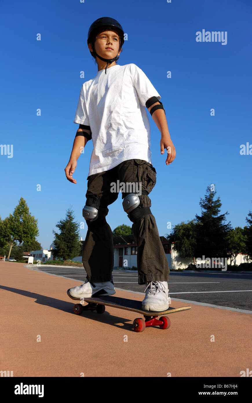 Junge auf einem Skateboard gegen blauen Himmel in der Sonne suchen Stockfoto