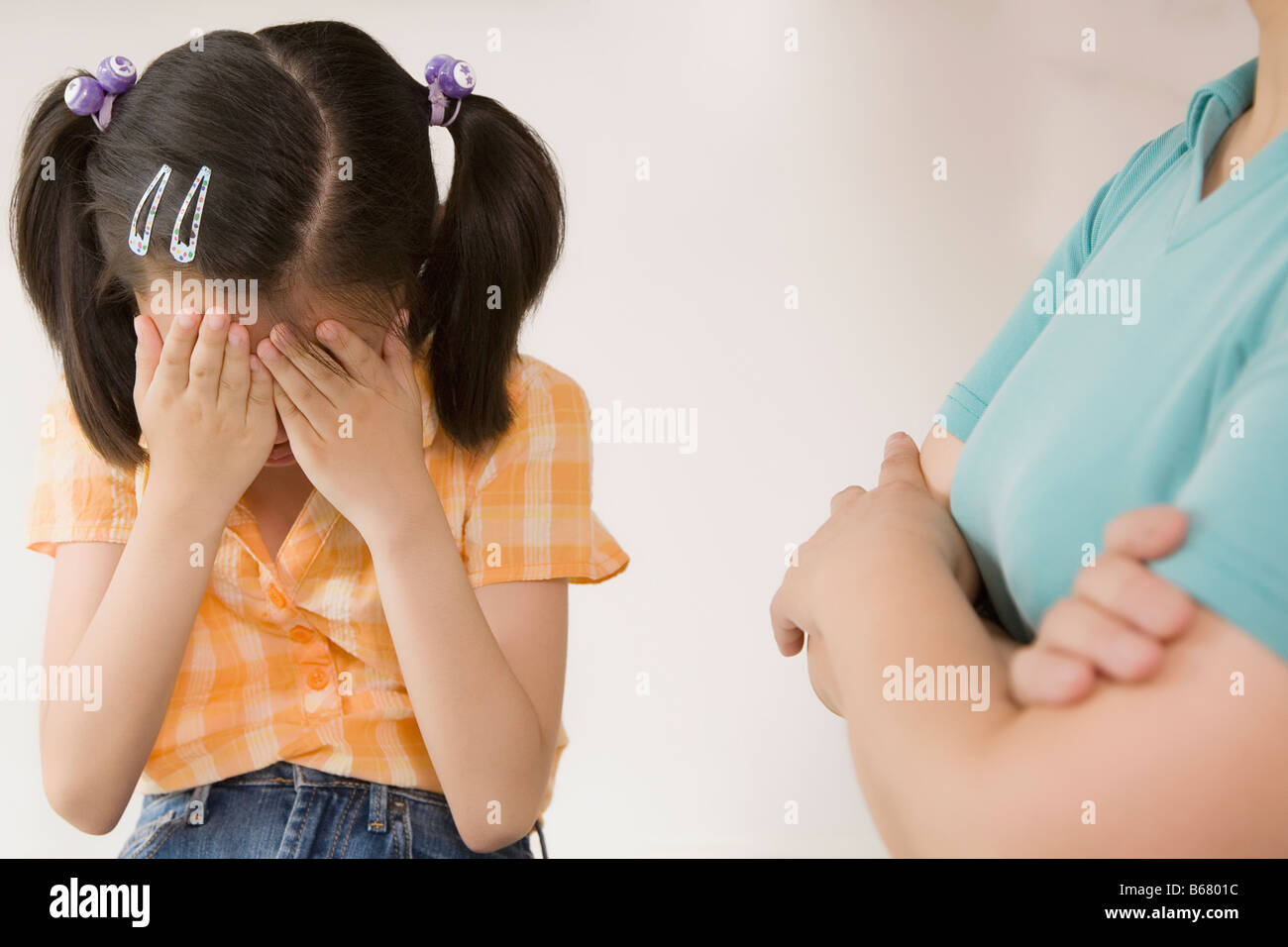 Nahaufnahme eines Mädchens versteckt ihr Gesicht und ihre Großmutter, die neben ihr Stand Stockfoto
