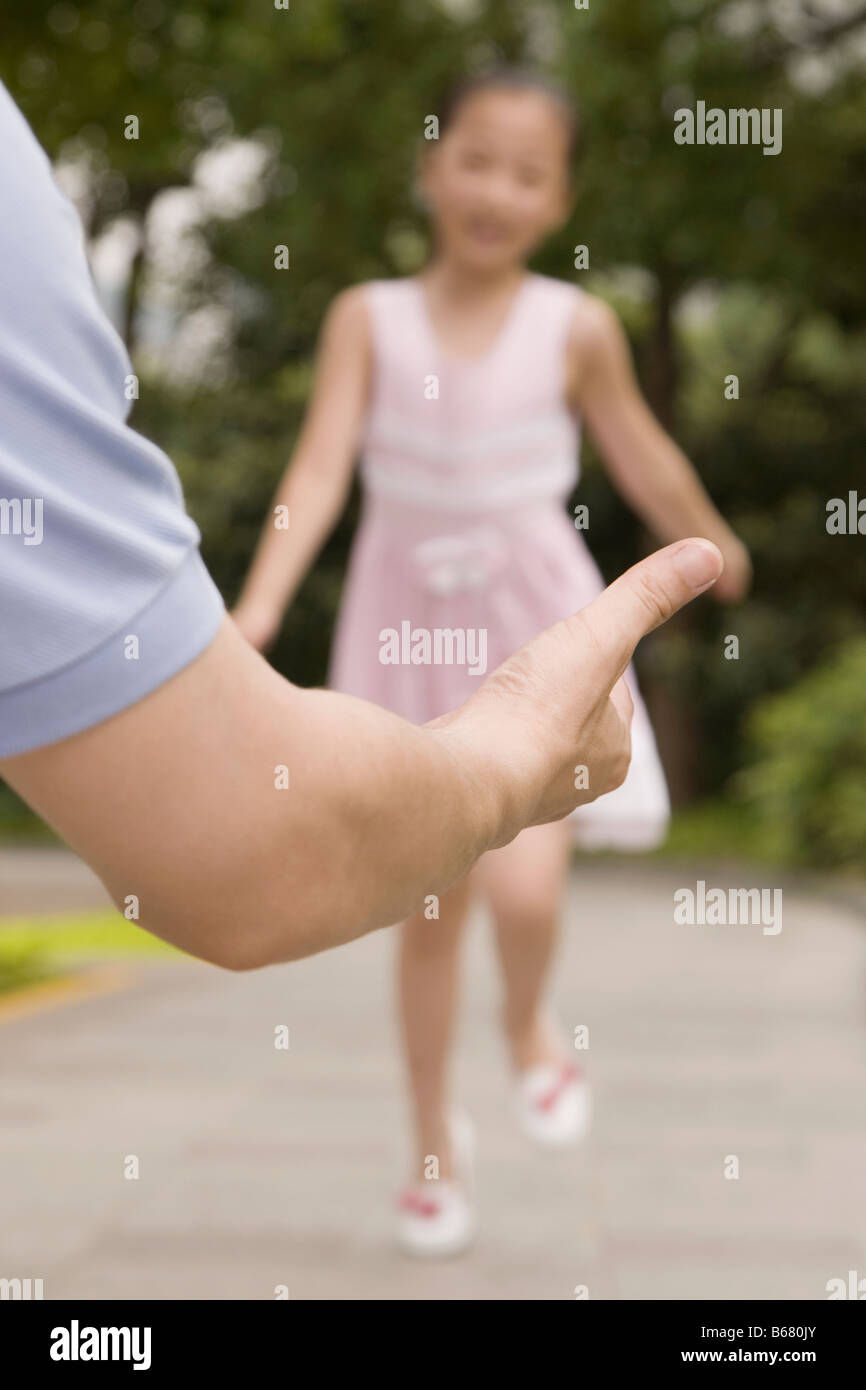 Mädchen ausgeführt, um ihren Vater in einem Garten zu umarmen Stockfoto