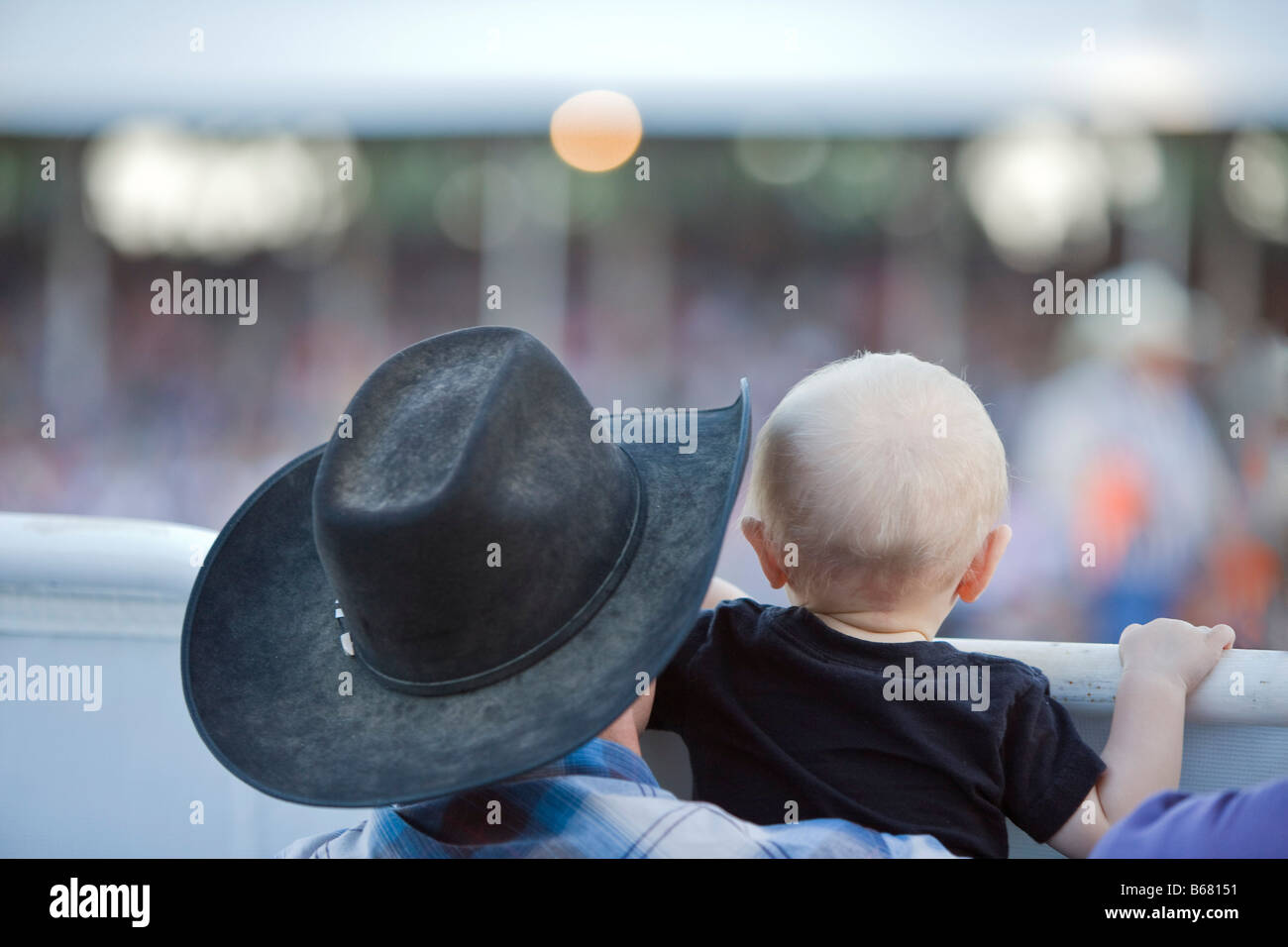 Rückansicht des Mannes hält Kind beim Rodeo, Belle Fourche, South Dakota, USA Stockfoto