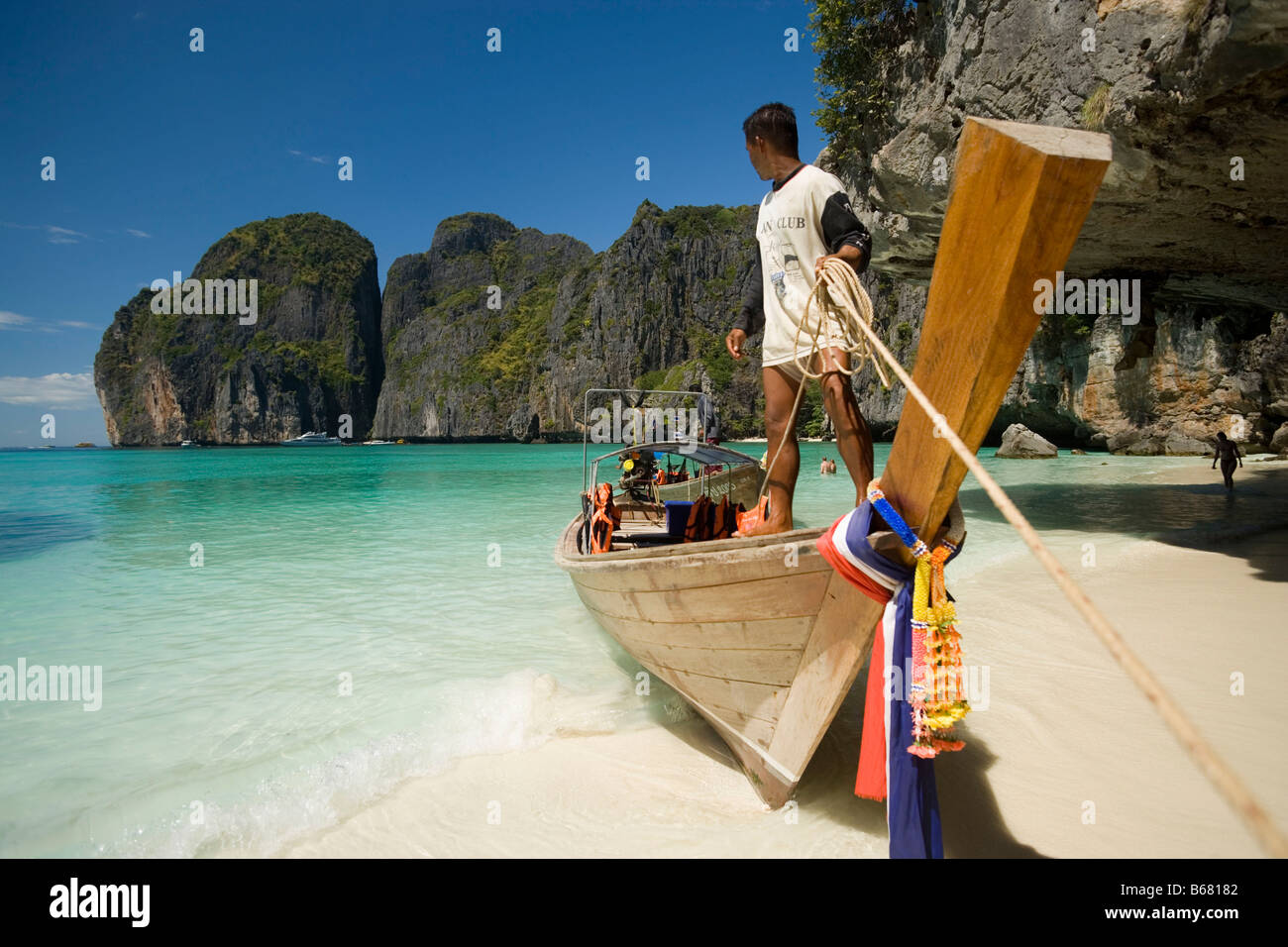 Bootsmann auf einem Longtail-Boot stehen und halten ein Seil, Maya Bay, eine wunderschöne malerische Lagune, berühmt für den Hollywood-Film "der Stockfoto