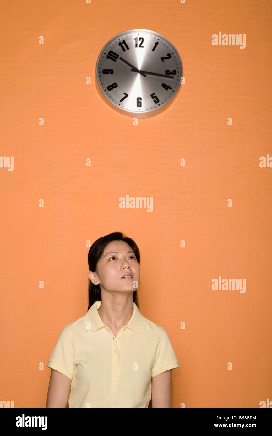 Weibliche Büroangestellte mit einer Uhr über dem Kopf Stockfoto