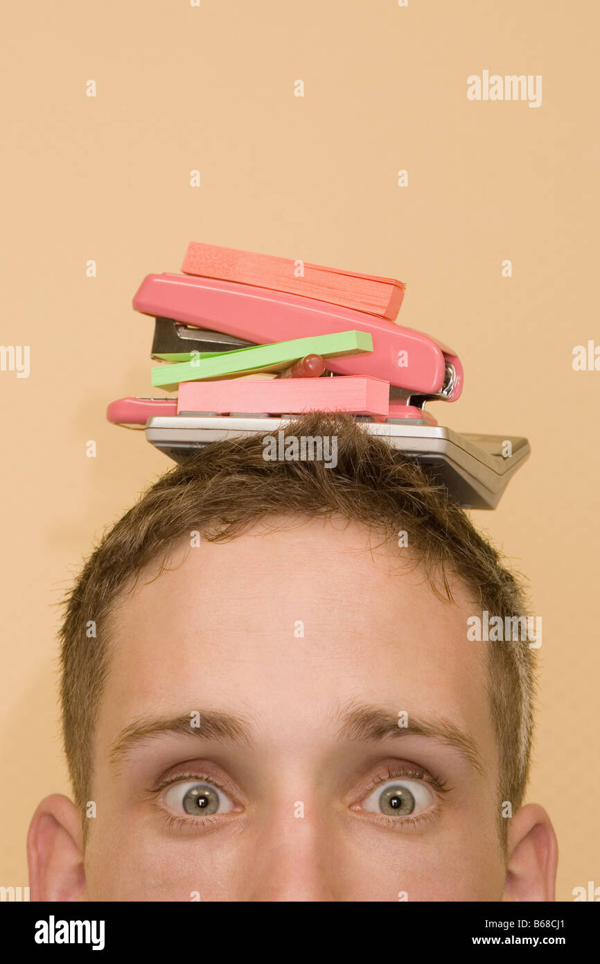 Porträt eines jungen Mannes mit Briefpapier Objekte auf dem Kopf Stockfoto