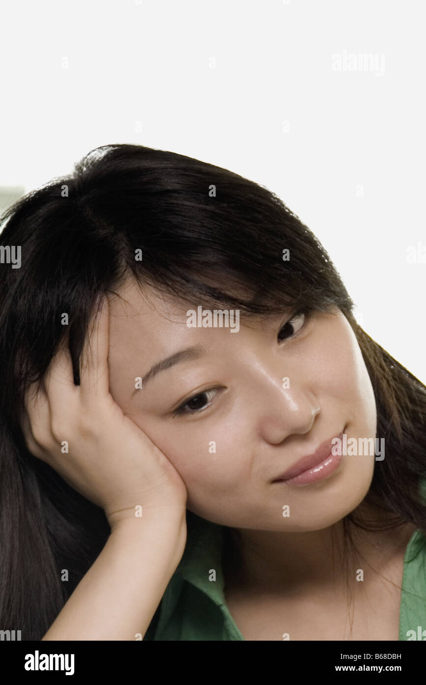 Nahaufnahme einer jungen Frau lehnte ihren Kopf auf ihre Hand und Grinsen Stockfoto