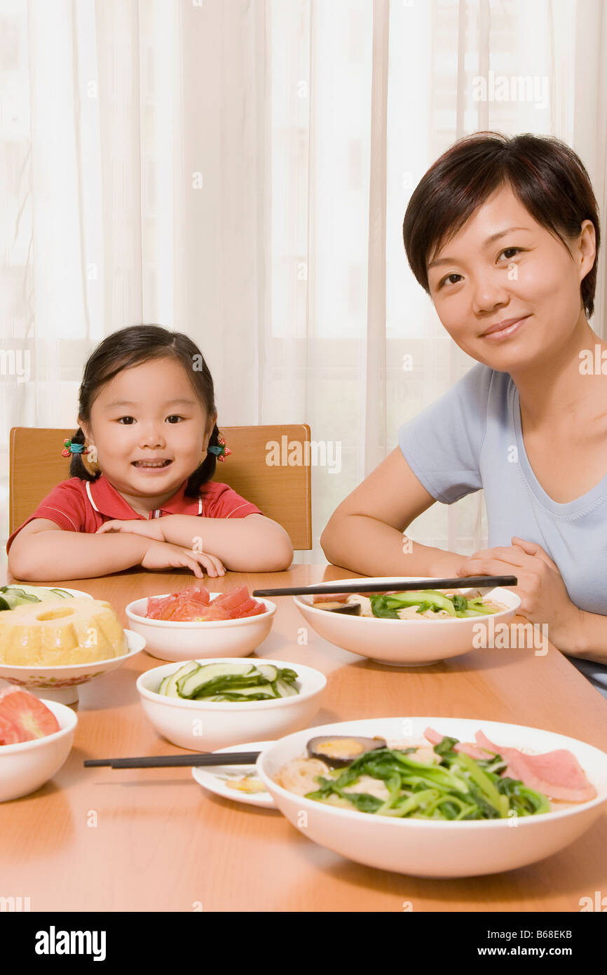 Porträt einer Mitte Erwachsene Frau mit ihrer Tochter an einem Esstisch sitzen Stockfoto