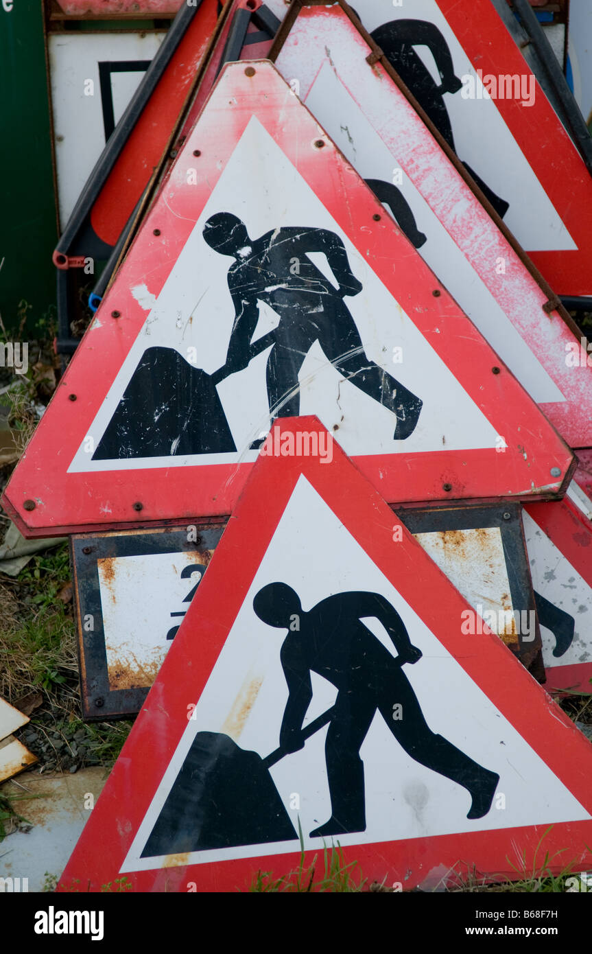 ein Stapel von dreieckigen "Men at Work" Baustellen Warnzeichen gespeichert gestapelt in einem Depot, UK Stockfoto