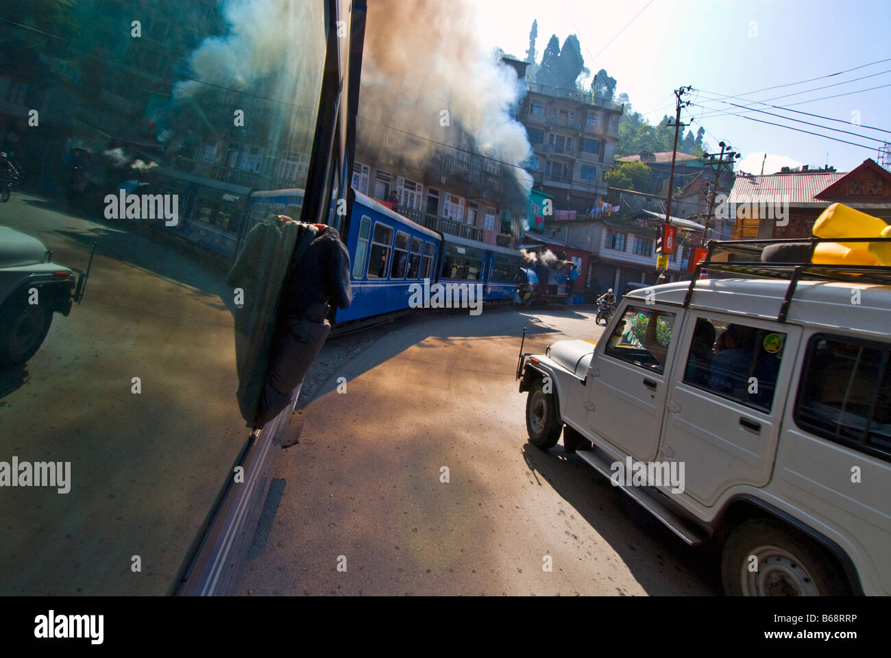 Die "Toy Train" der Darjeeling Himalayan Railway windet sich inmitten von Straßenverkehr auf den Straßen von Darjeeling Stockfoto