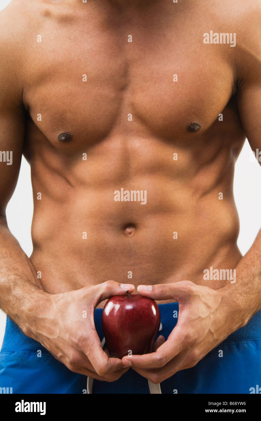 Drilliche Mann, hält Apfel, Mittelteil Stockfoto