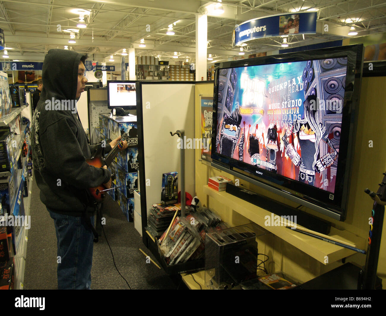 Ein Teen Männchen versuchen, die neuesten Guitar Hero zu einem Elektronik-Shop-Display. Stockfoto