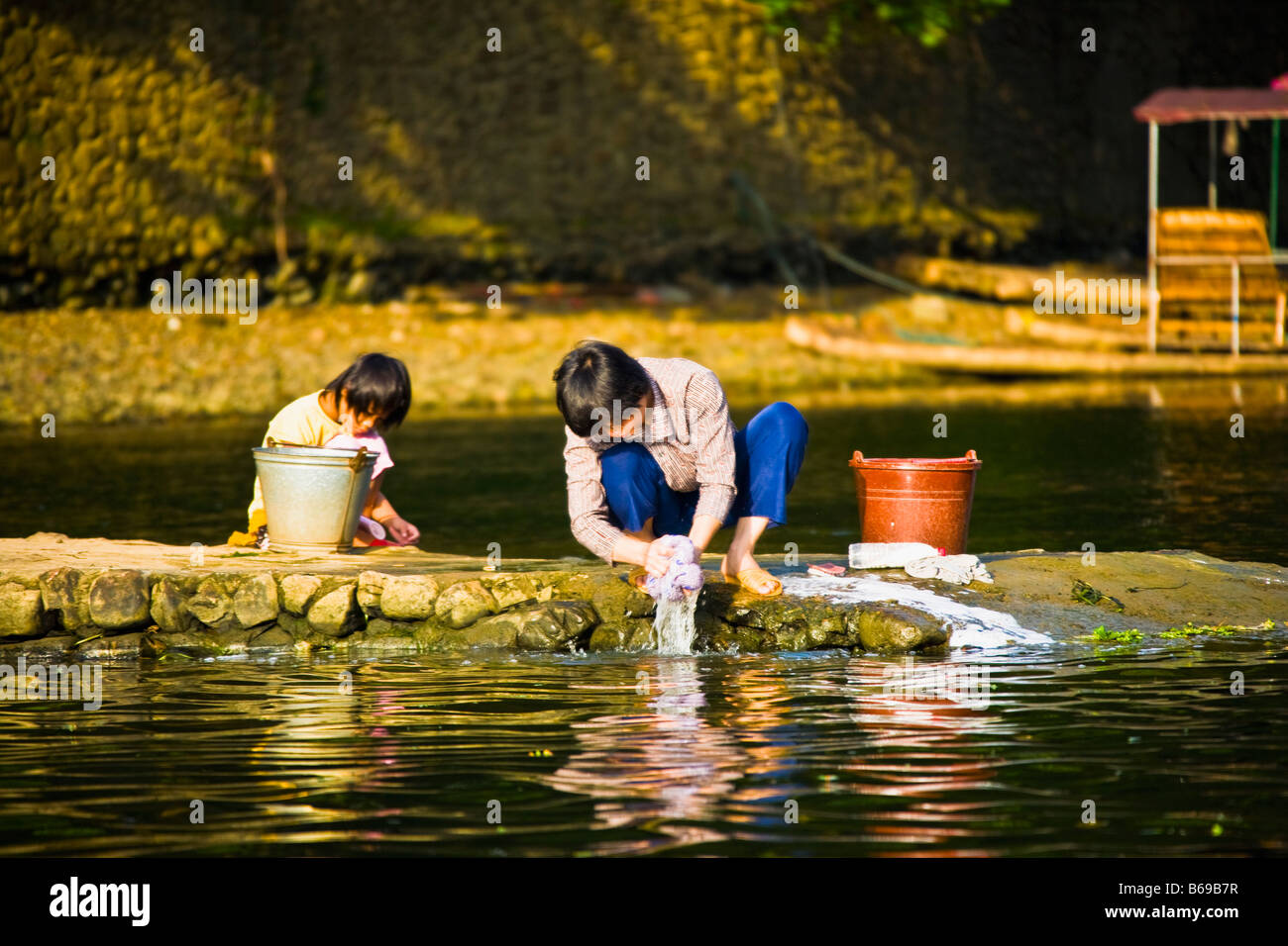 Junge Frau mit ihrer Tochter, die Wäsche an einem Fluss, Li-Fluss, XingPing, Yangshuo, Provinz Guangxi, China Stockfoto