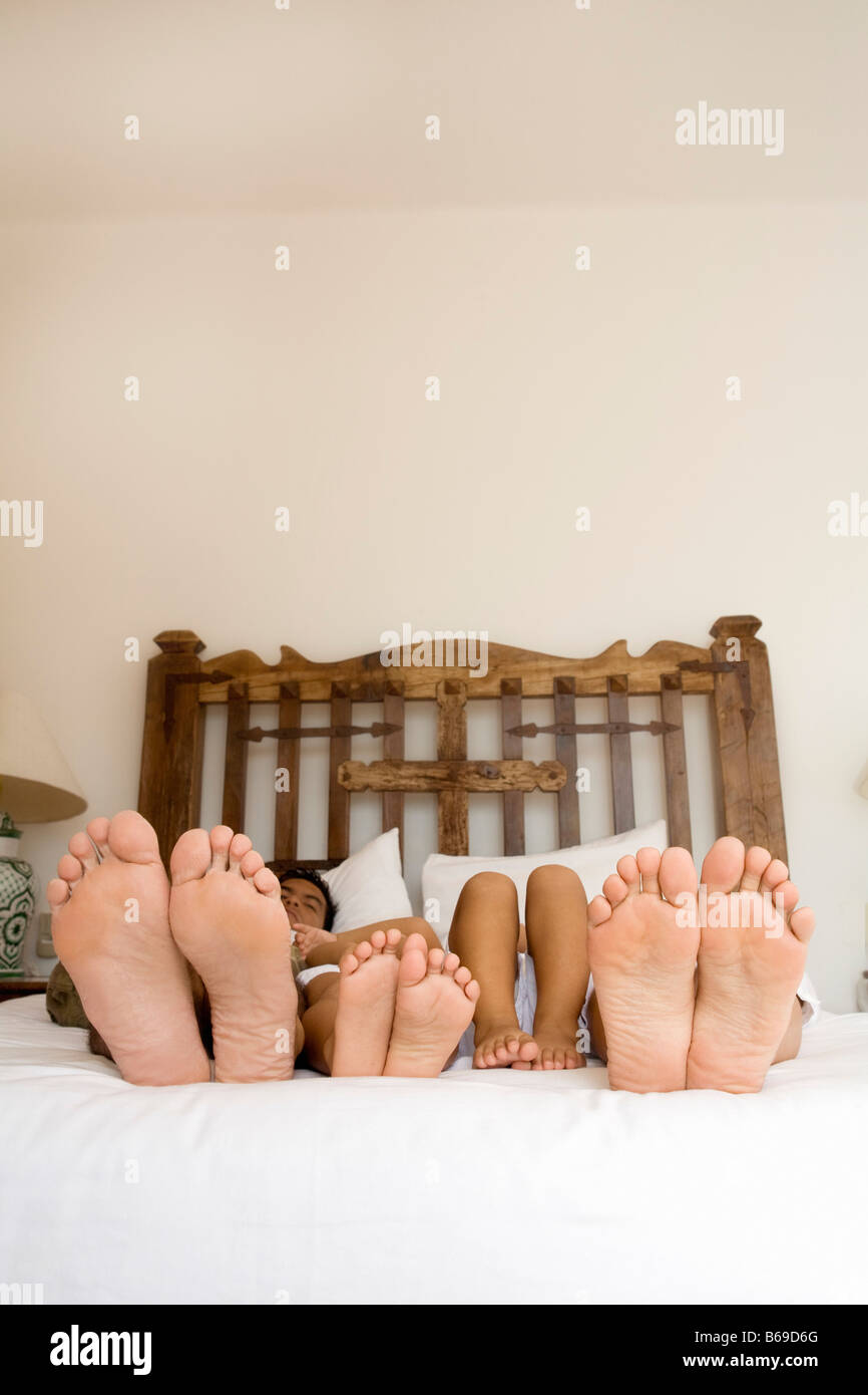 Sohlen des Paares und ihrer Kinder zu Fuß auf dem Bett Stockfoto