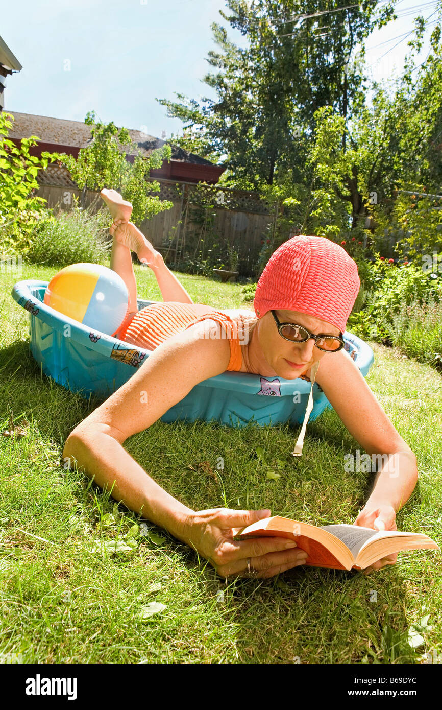 Frau liegend in ein Planschbecken und ein Buch zu lesen Stockfoto