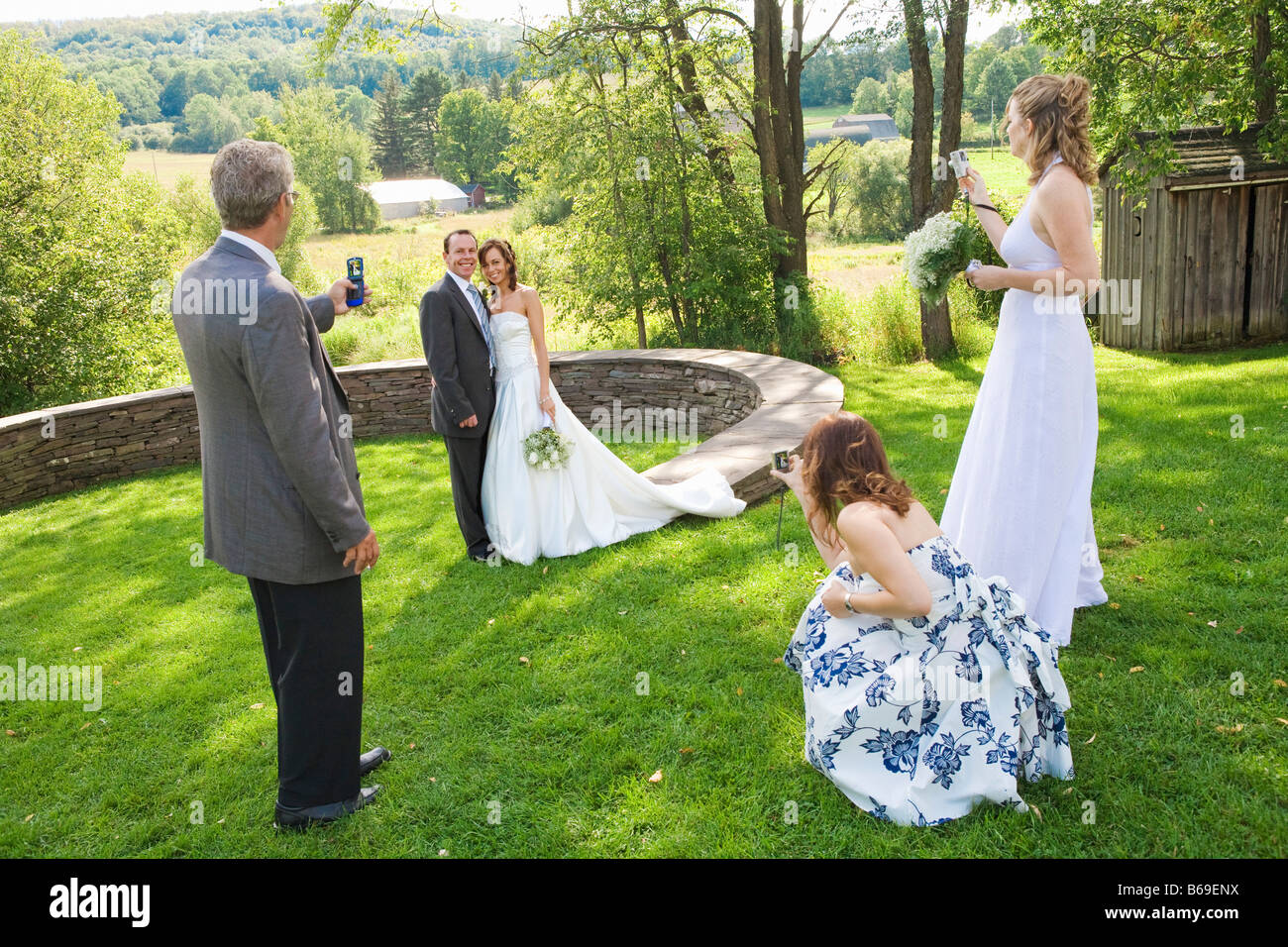 Mann mit zwei Frauen fotografieren ein Brautpaar in einem Park, East Meredith, New York State, USA Stockfoto