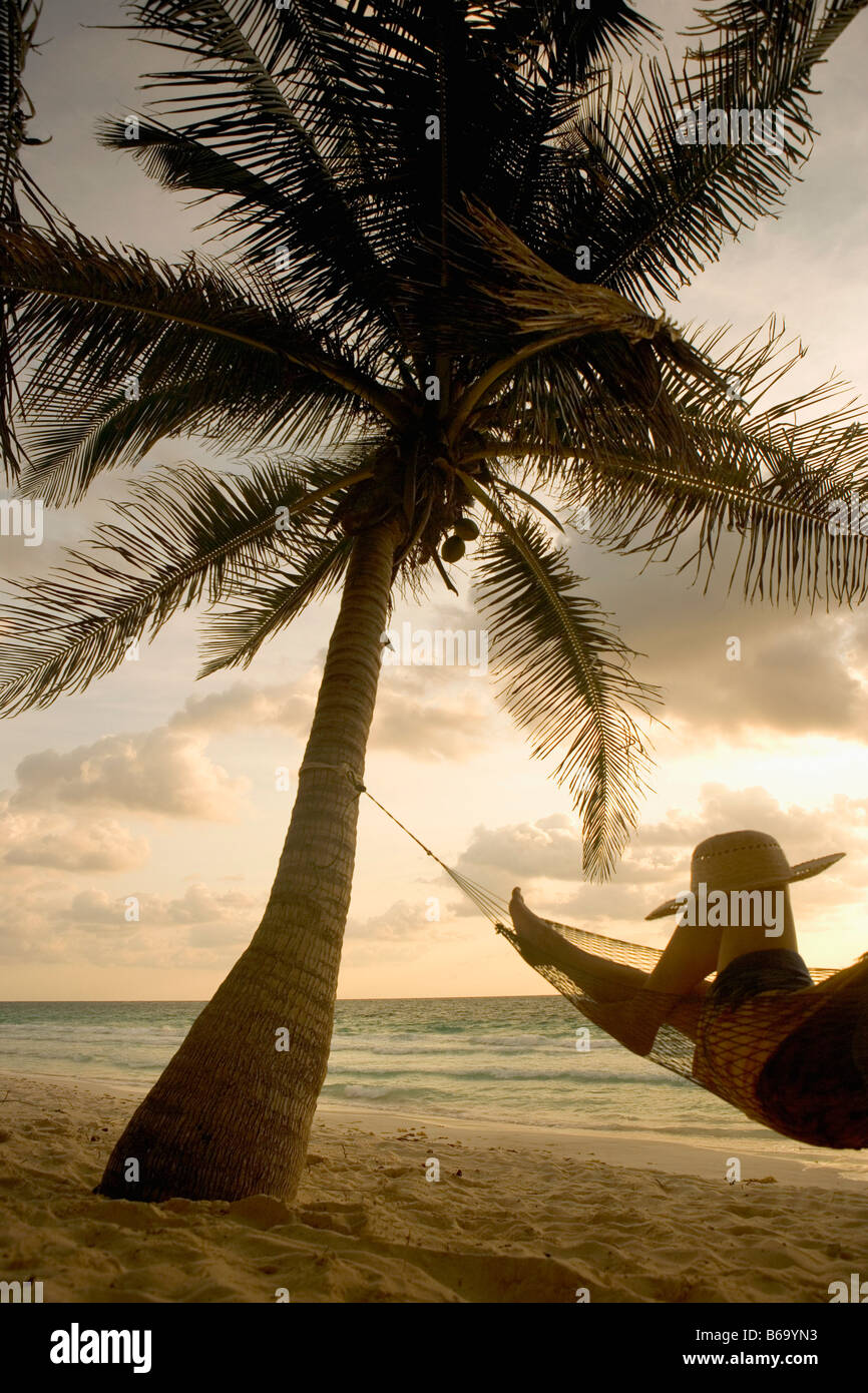 Mexiko, Tulum, Quintana Roo Tourist (Frau) in der Hängematte unter Palmen am Strand Stockfoto