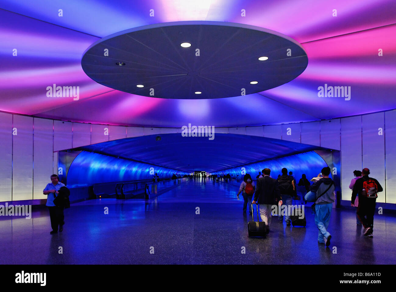 Reisende zu Fuß innerhalb und außerhalb der Tunnel zwischen den Terminals am Flughafen bei Licht und Ton zeigen Detroit Michigan Stockfoto