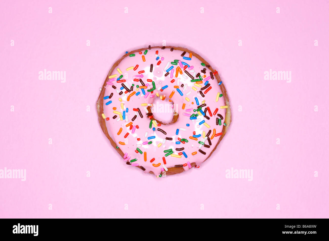 Krapfen mit rosa Zuckerguss und Streusel auf rosa Hintergrund Stockfoto