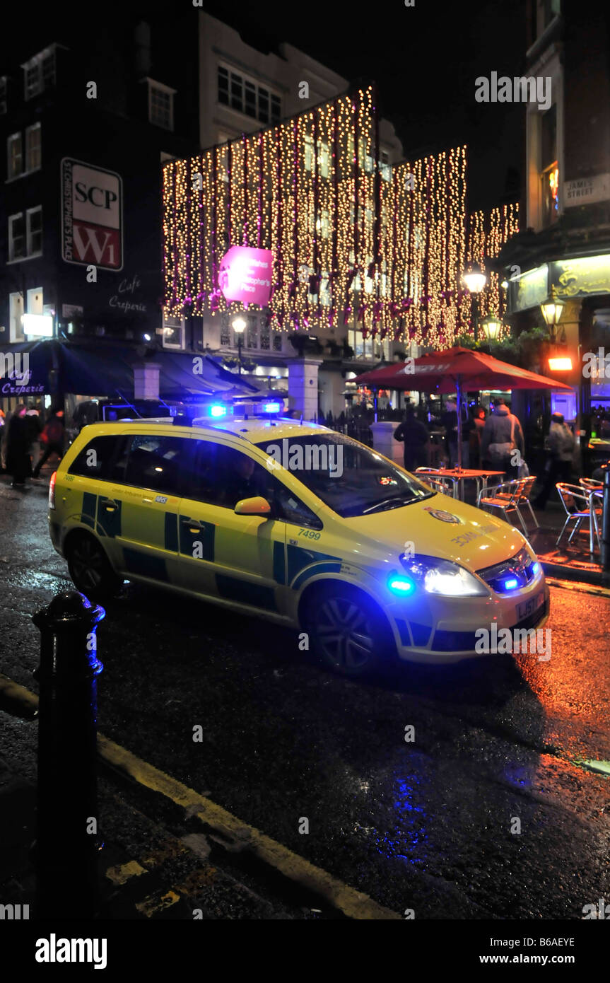 London West End Nacht Ambulanz Auto Fahrer auf Notfall 999 Anruf stecken in der Hauptverkehrszeit Verkehrsstau blaue Lichter und beleuchtete Weihnachtsdekorationen uk Stockfoto