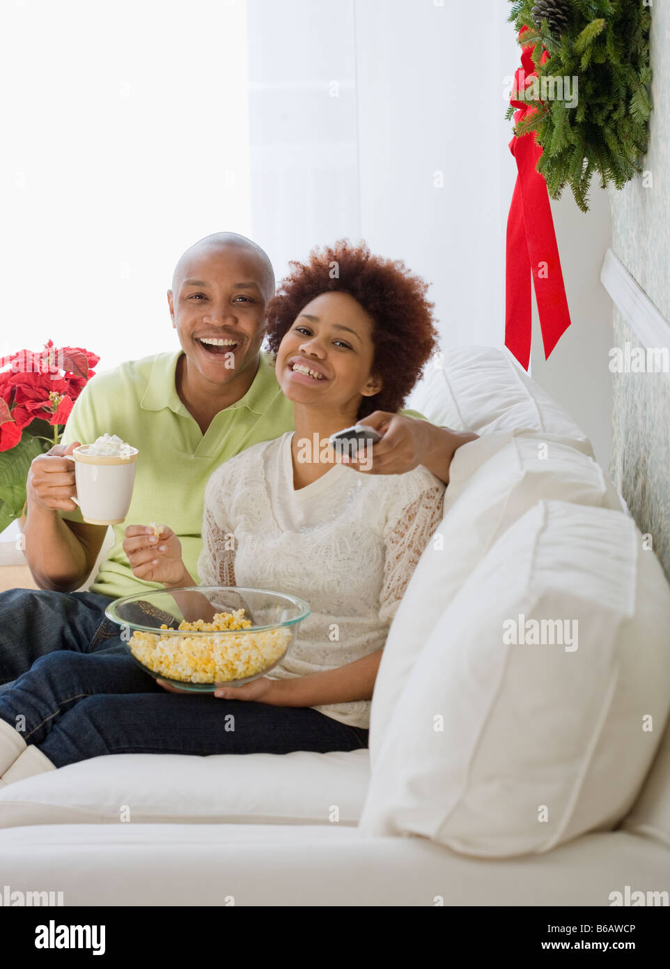 African Paar vor dem Fernseher mit Popcorn und heiße Schokolade Stockfoto