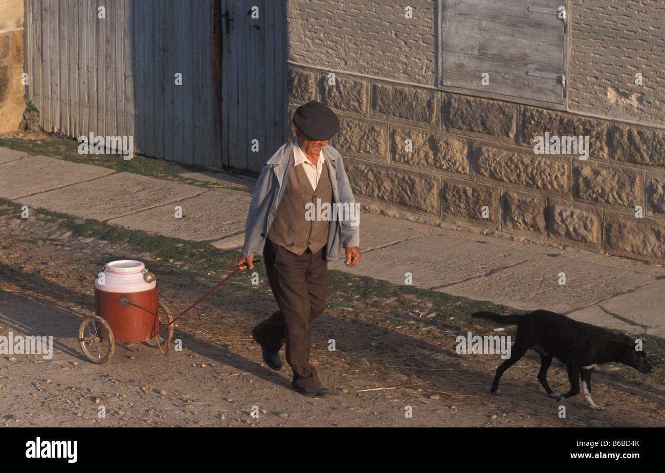 Mann zu Fuß in der Hauptstraße in Szekelyderz oder Dariju Dorf ziehen eine Milch produzieren in der hand Warenkorb Stockfoto