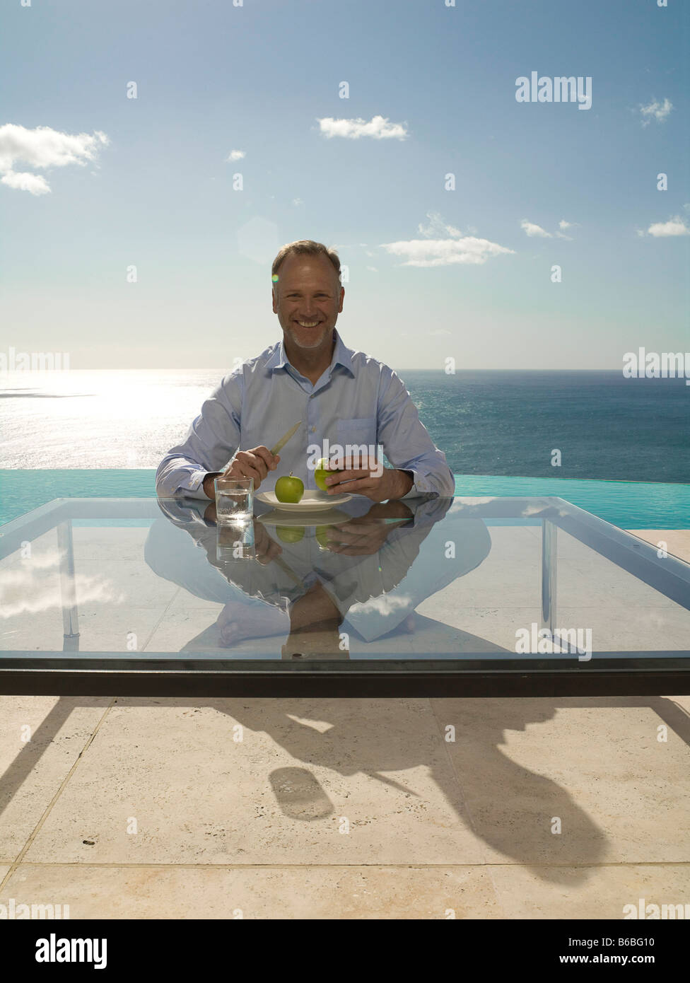 Porträt des Mannes Apfel schälen und lächelnd am Pool Stockfoto