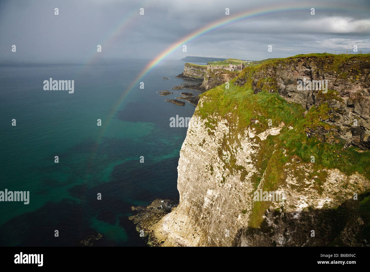 Ein doppelter Regenbogen über den Klippen am weißen Felsen und Blick Richtung Dunluce Castle an der Küste von North Antrim, Nordirland Stockfoto