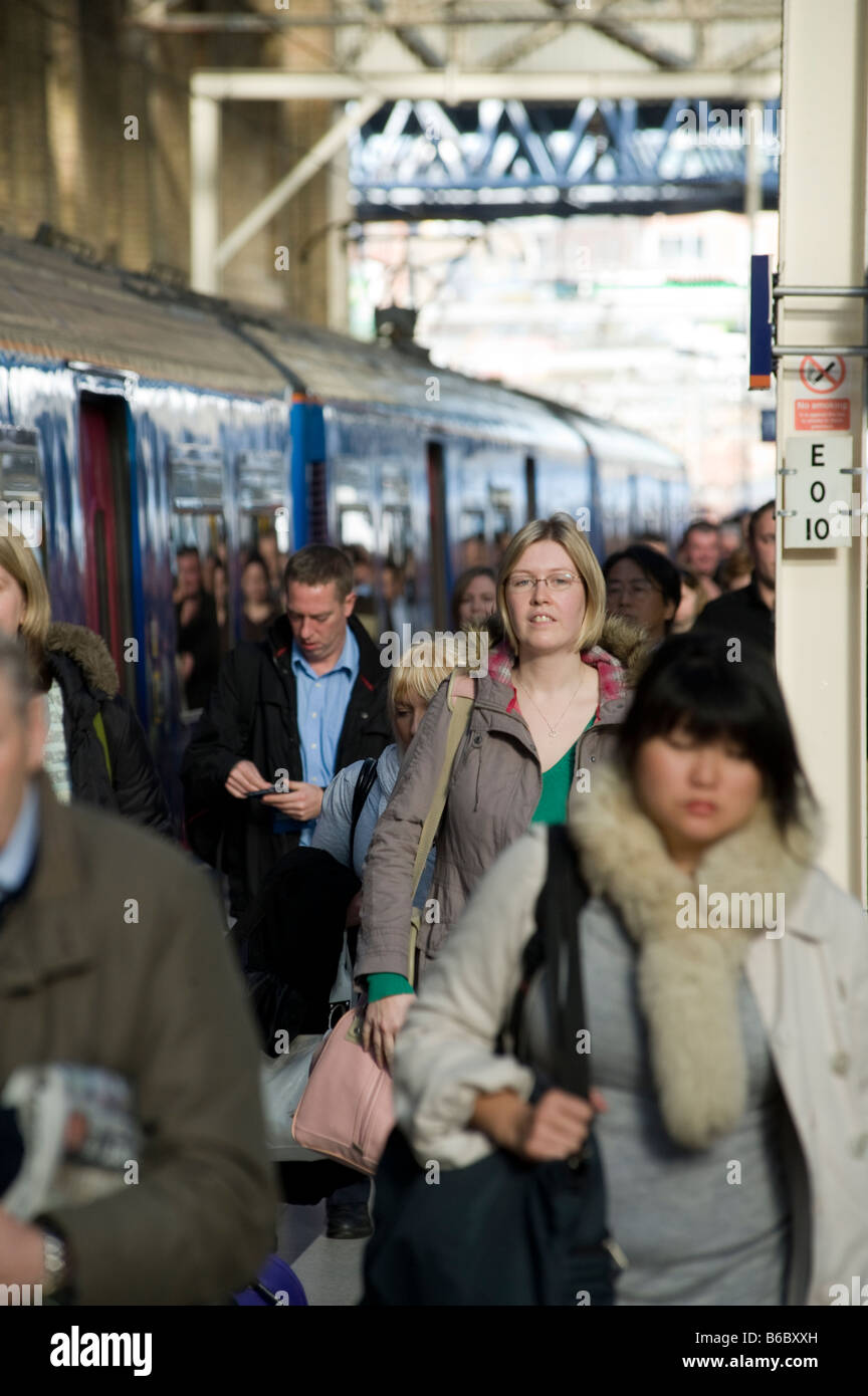Passagiere, die aus einem Zug auf einen überfüllten Bahnhofssteig in Großbritannien steigen. Stockfoto