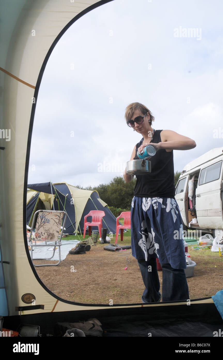 eine Frau mit einem Kaffeetopf in einer schmuddeligen Wochen camping Stockfoto