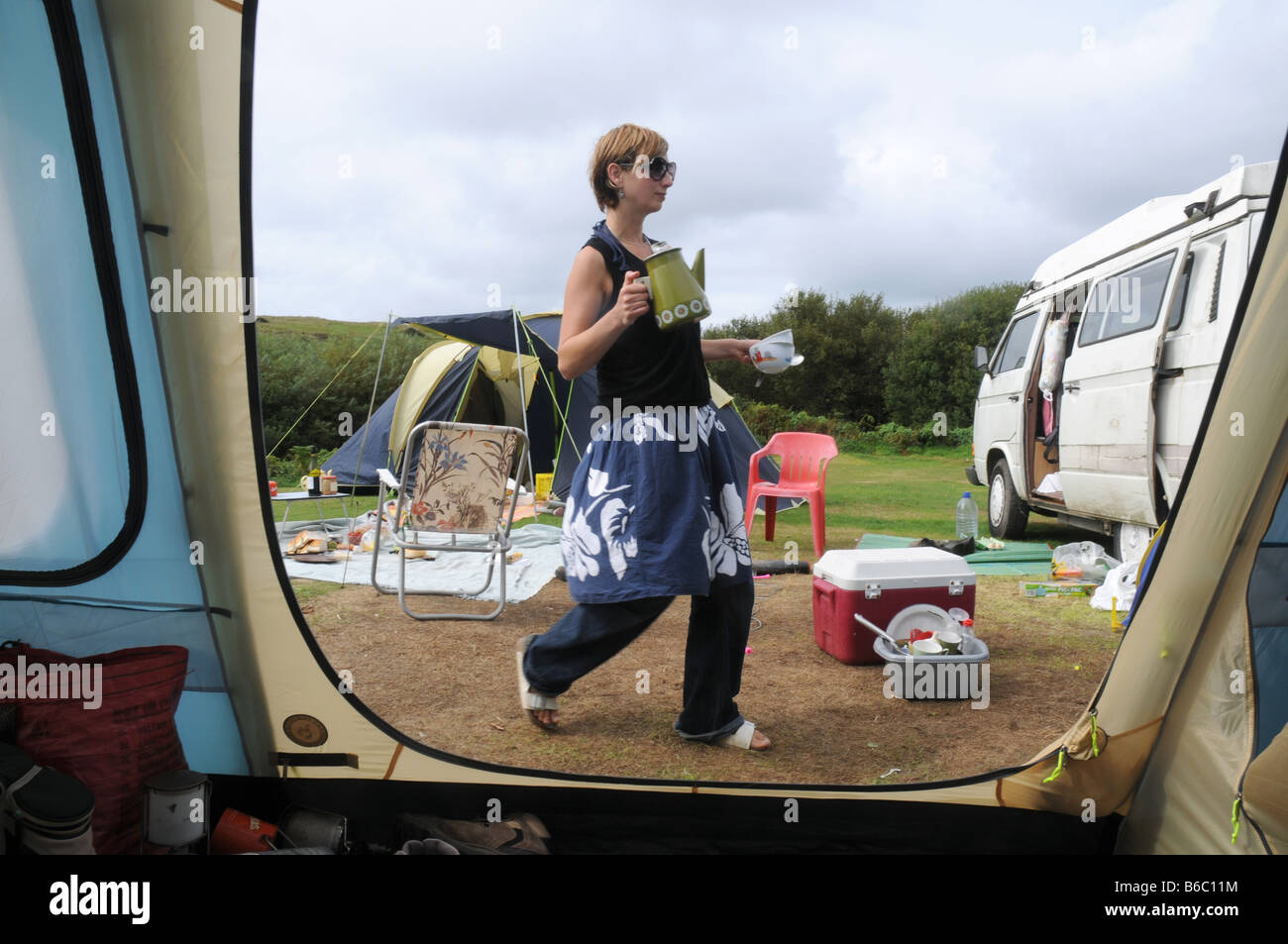 eine Frau mit einem Kaffeetopf in einer schmuddeligen Wochen camping Stockfoto