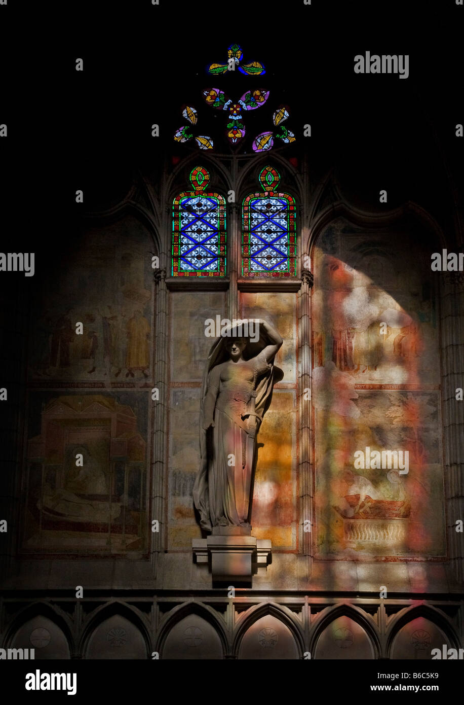 Statue beleuchtet vom Licht ein Buntglasfenster im 14. Jahrhundert Katharer gotische St. Nazaire Kathedrale, Bezier, Languedoc-Roussillon, Frankreich Stockfoto