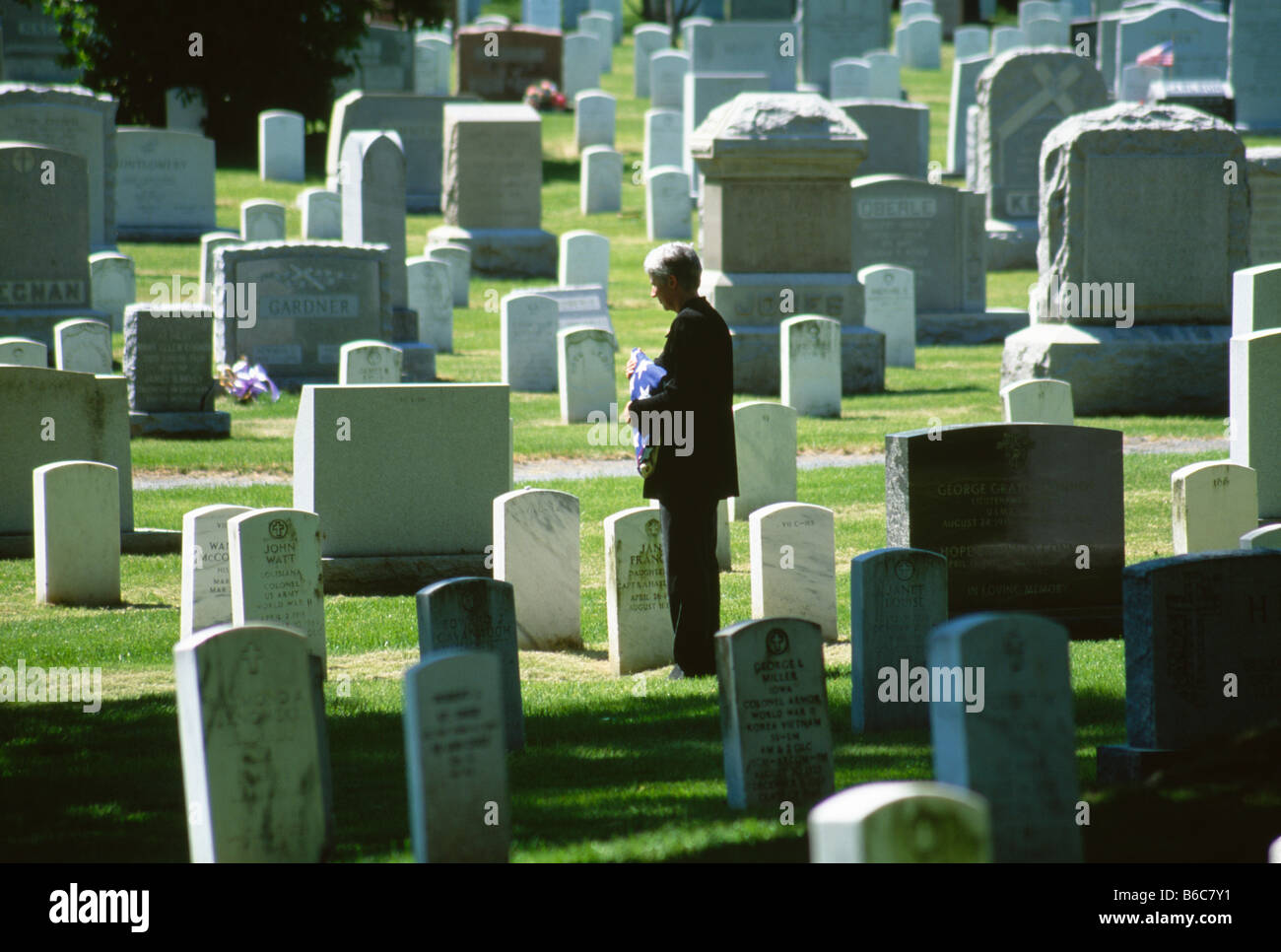 Reife Frau mit US-Flagge im Friedhof Stockfoto