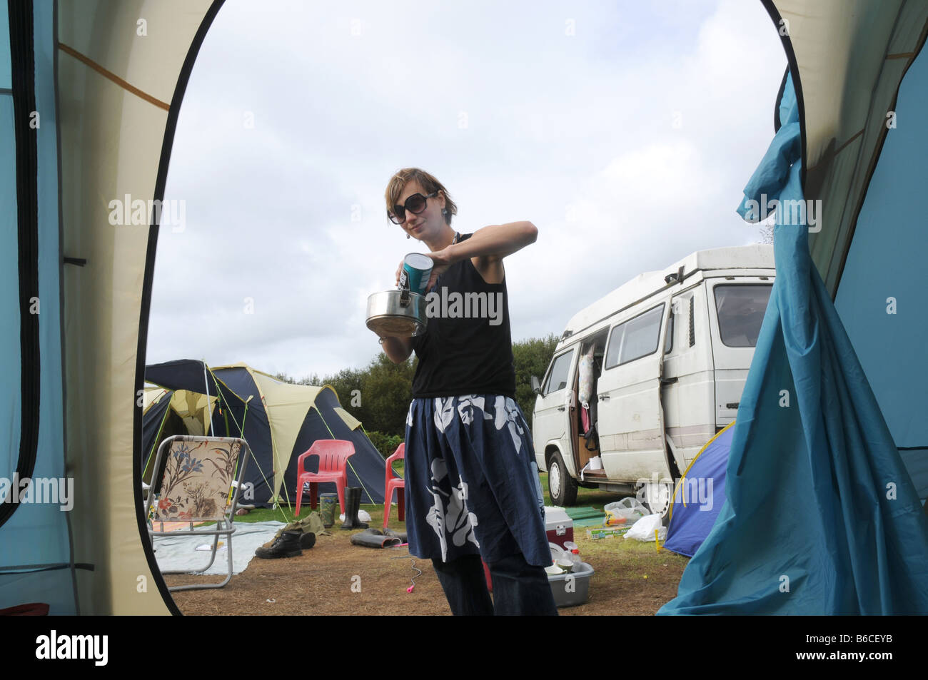 eine Frau mit einem Kaffeetopf in einer schmuddeligen Wochen camping Stockfoto