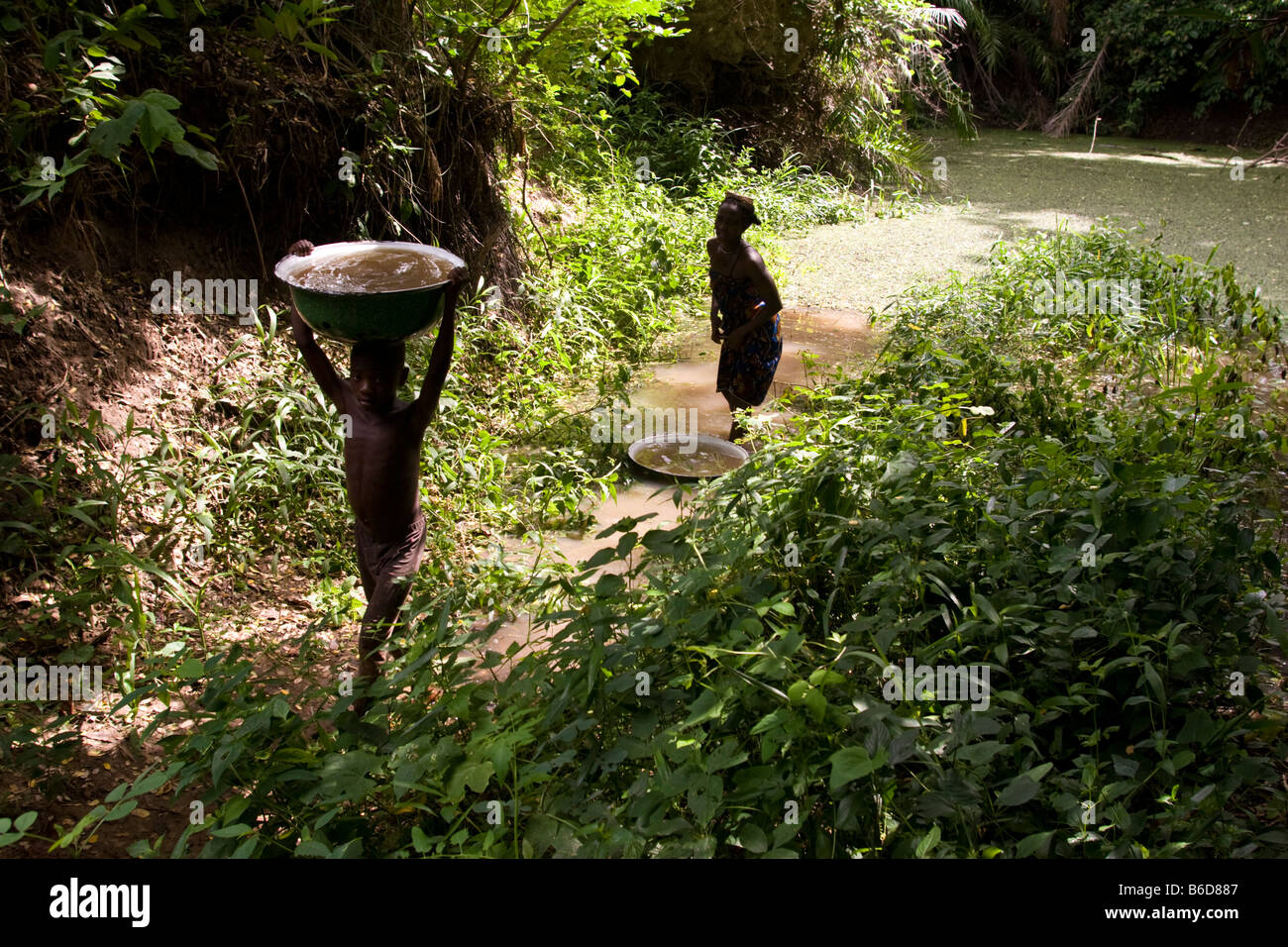 Eine junge Carring Schüssel mit schmutzigem Wasser nach Hause, Dassa, Benin, Westafrika. Stockfoto