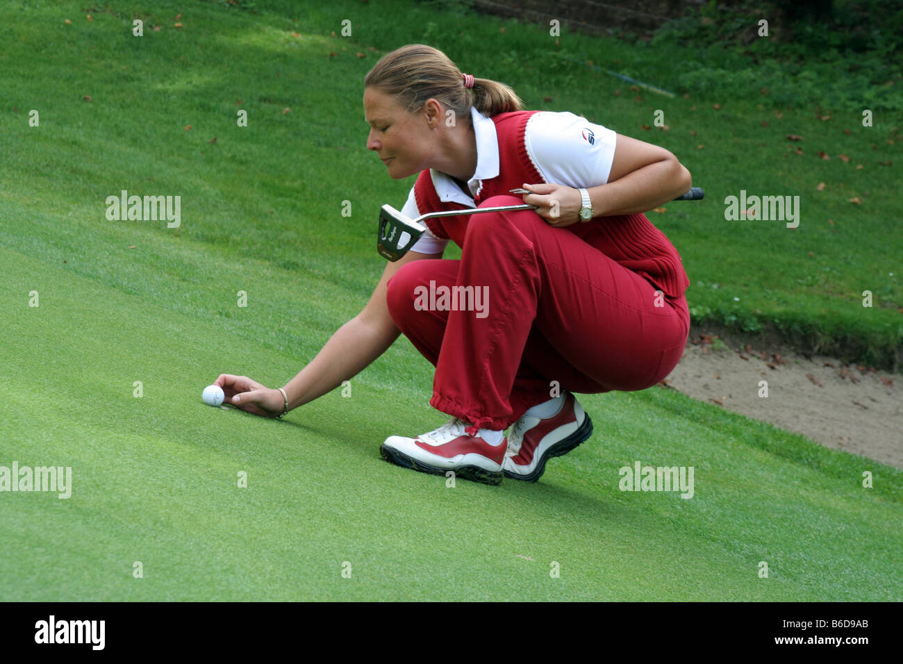 Frau Unternahme der Golfball auf grün. Stockfoto