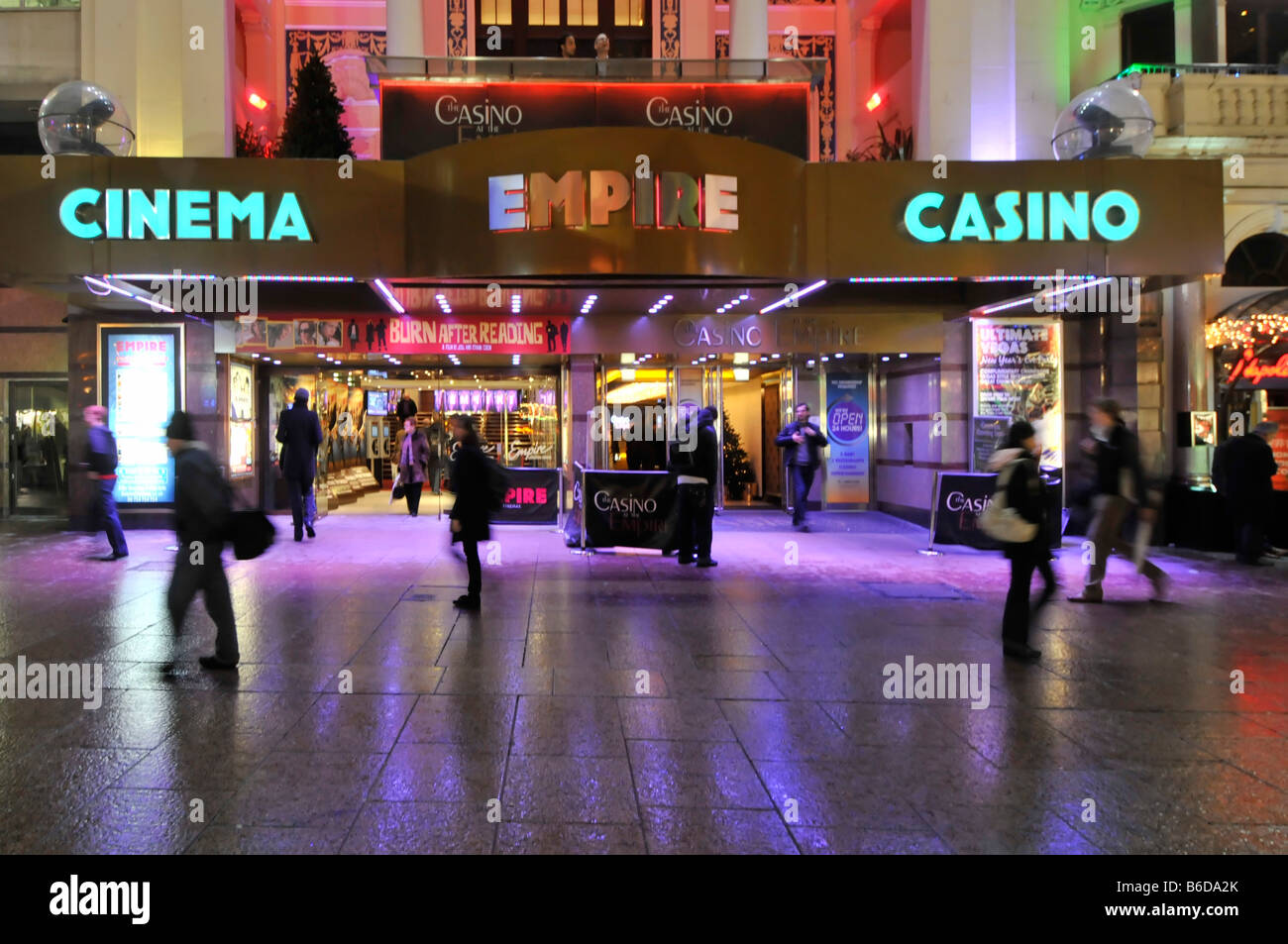 Abends Blick auf die Menschen auf dem Bürgersteig vor dem Empire Leicester Square Kino Casino Unterhaltungsgelände, in leuchtenden Farben, Flutlicht London England Großbritannien Stockfoto