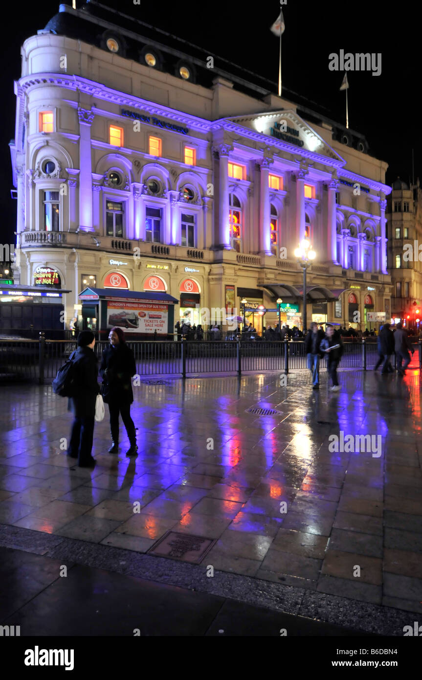 Beleuchtetes Londoner Trocadero-Gebäude viktorianische Barockfassade im Inneren des Unterhaltungs- und Einkaufskomplexes farbenfrohe Lichter, die sich in nassen Straßen Großbritanniens widerspiegeln Stockfoto