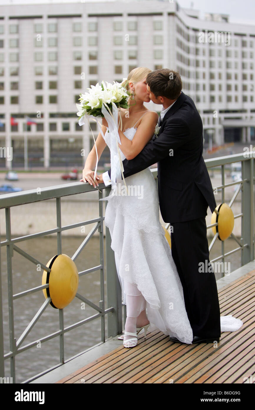 Brautpaar küssen im Geschaeftsviertel Wasser im Hintergrund Stockfoto