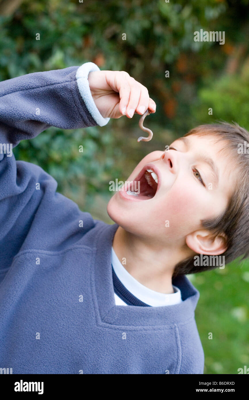 Junge, die vorgibt, einen Wurm zu essen. Dies ist ein Regenwurm ein Beschäftigungsförderung Wurm gefunden im Boden. Stockfoto