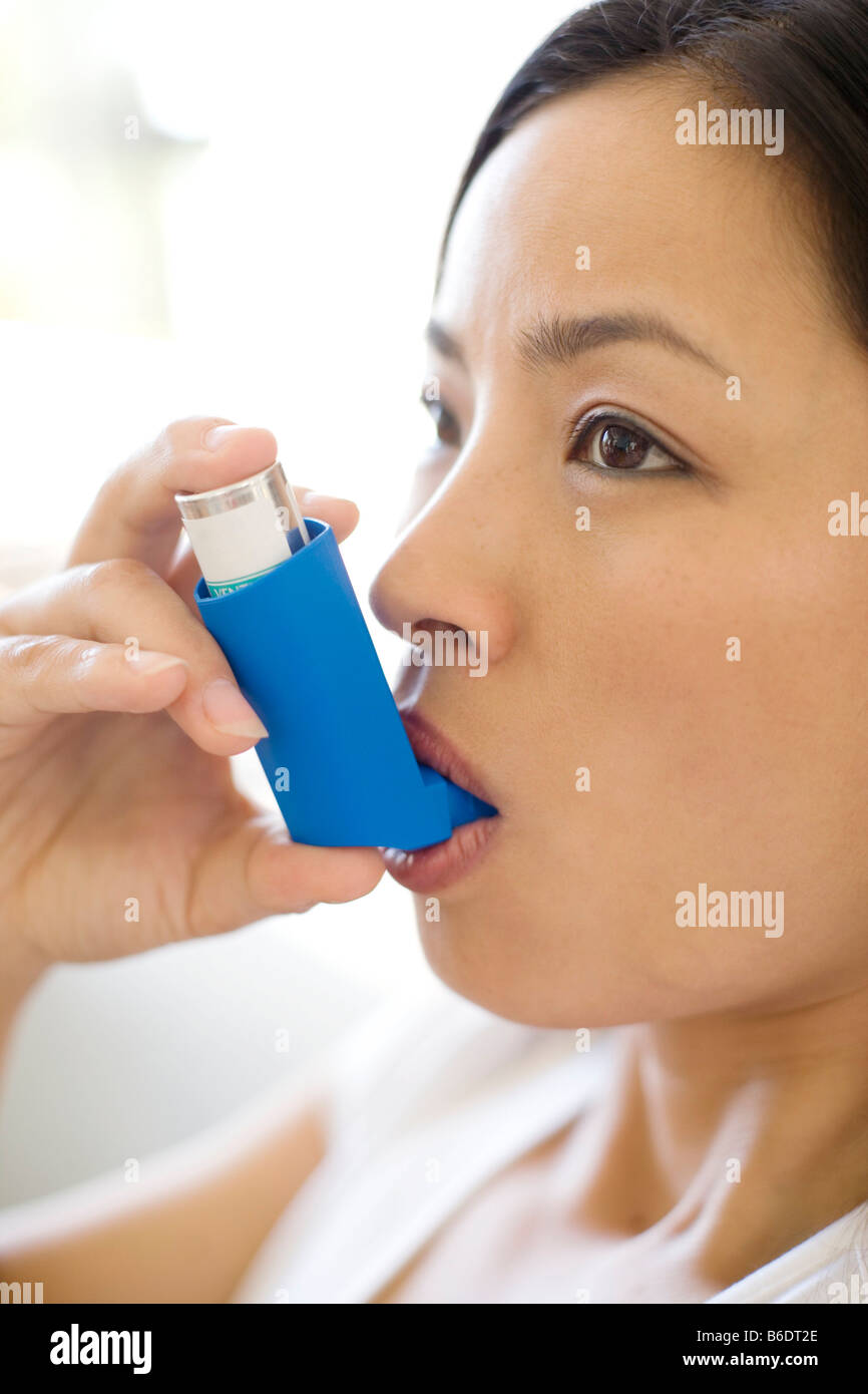 Asthma-Inhalator verwenden. Frau mit einem Inhalator, um einen Asthma-Anfall zu behandeln. Der Inhalator enthält bronchienerweiternde Medikamente. Stockfoto