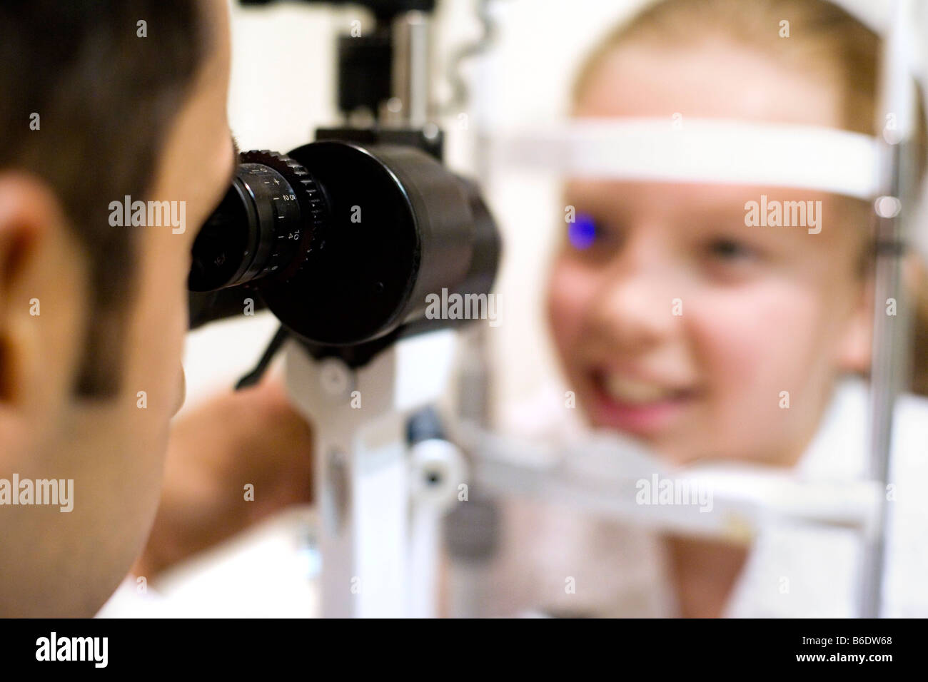 Augenuntersuchung. Optiker mit einer Spaltlampe, um ein zehnjähriges Mädchen Augen zu untersuchen. Dieses Instrument scheint einen feinen Lichtstrahl. Stockfoto