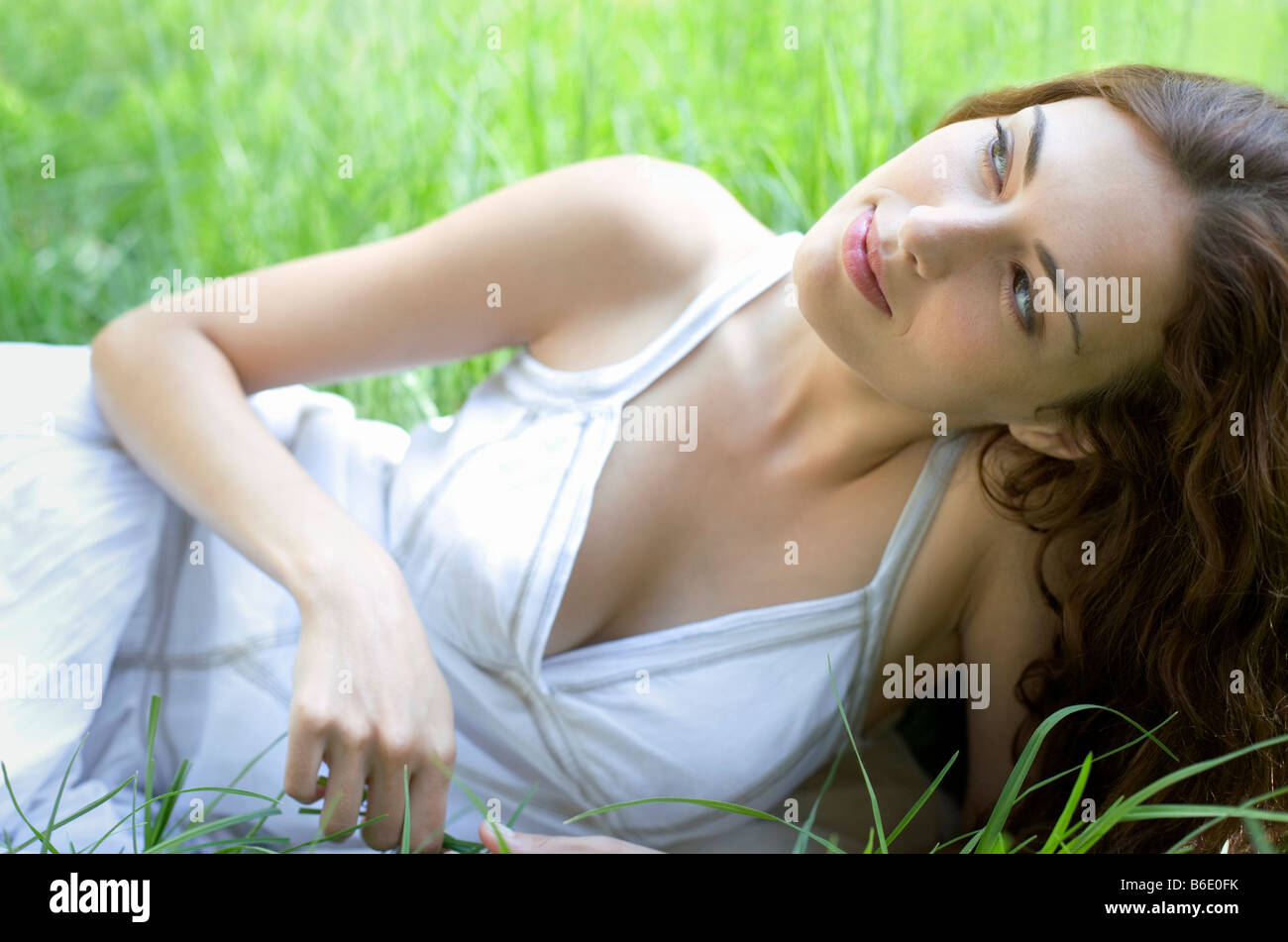 Nachdenkliche Frau liegt auf dem Rasen Stockfoto