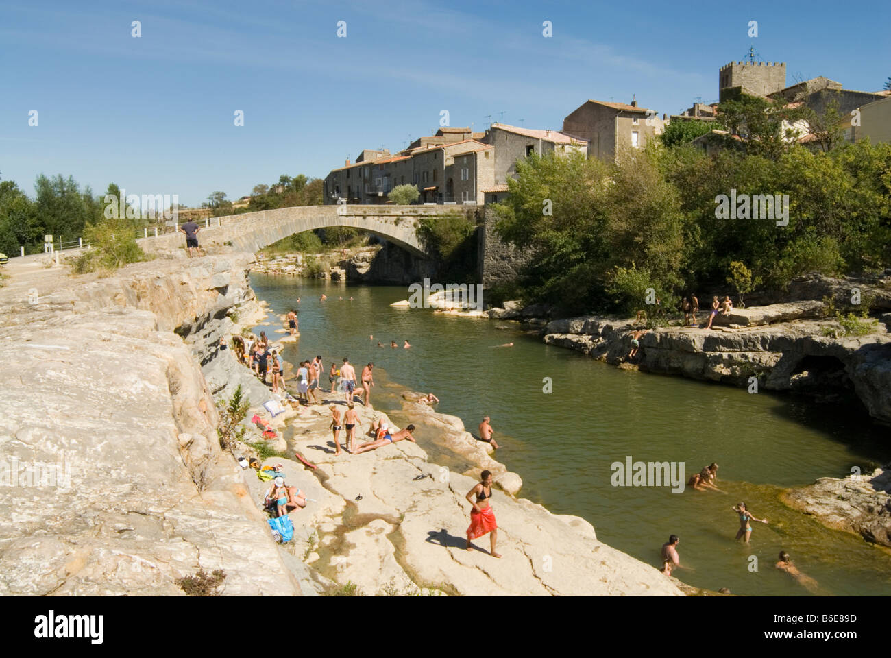 Urlauber, Schwimmen in den Gewässern des Flusses Orbieu mit dem Dorf Ribaute Les Corbieres Languedoc in der Ferne. Stockfoto